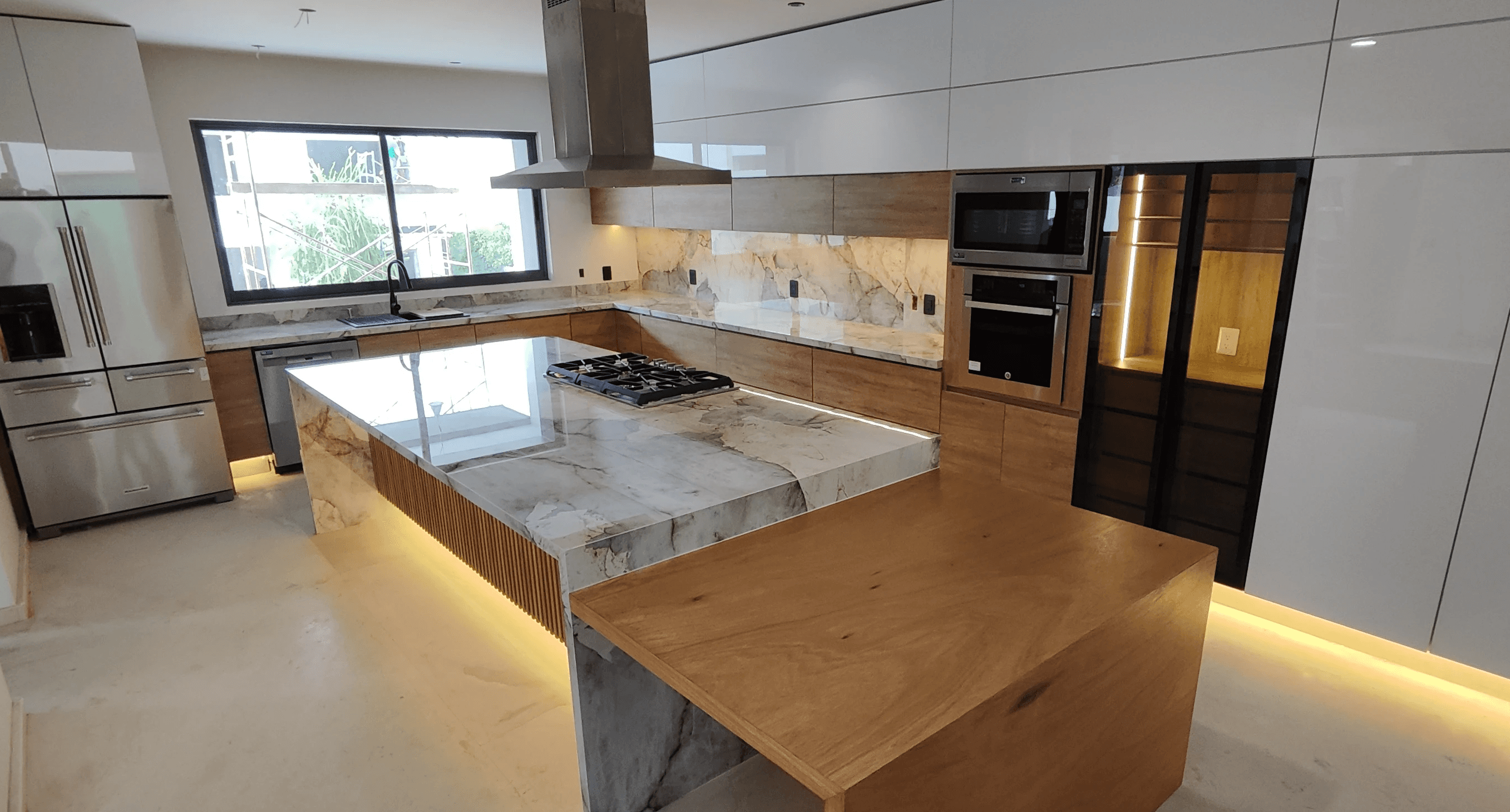 Modern indoor space with large glass doors, lush greenery, and a cozy seating area visible beyond.