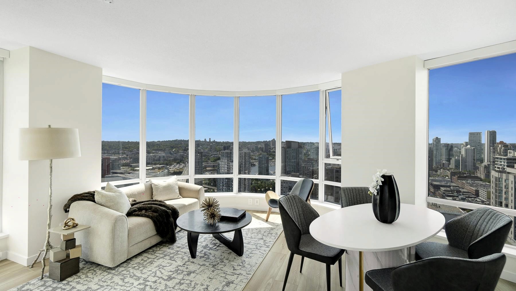 A modern living room with large windows, featuring stylish furniture and a breathtaking city view.