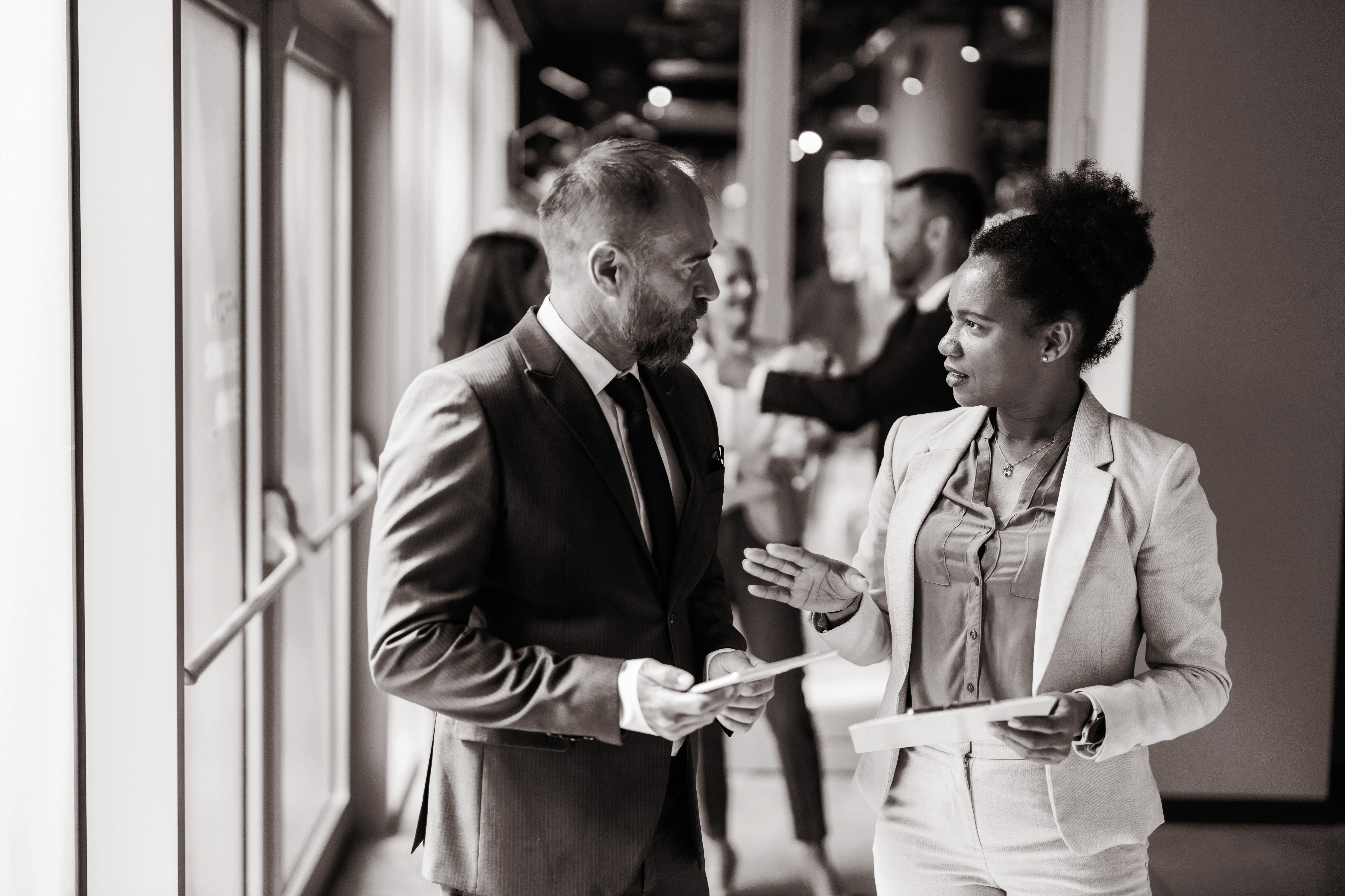 In a place of work full of light, two business persons engage in a cheerful discussion, showcasing teamwork, communication