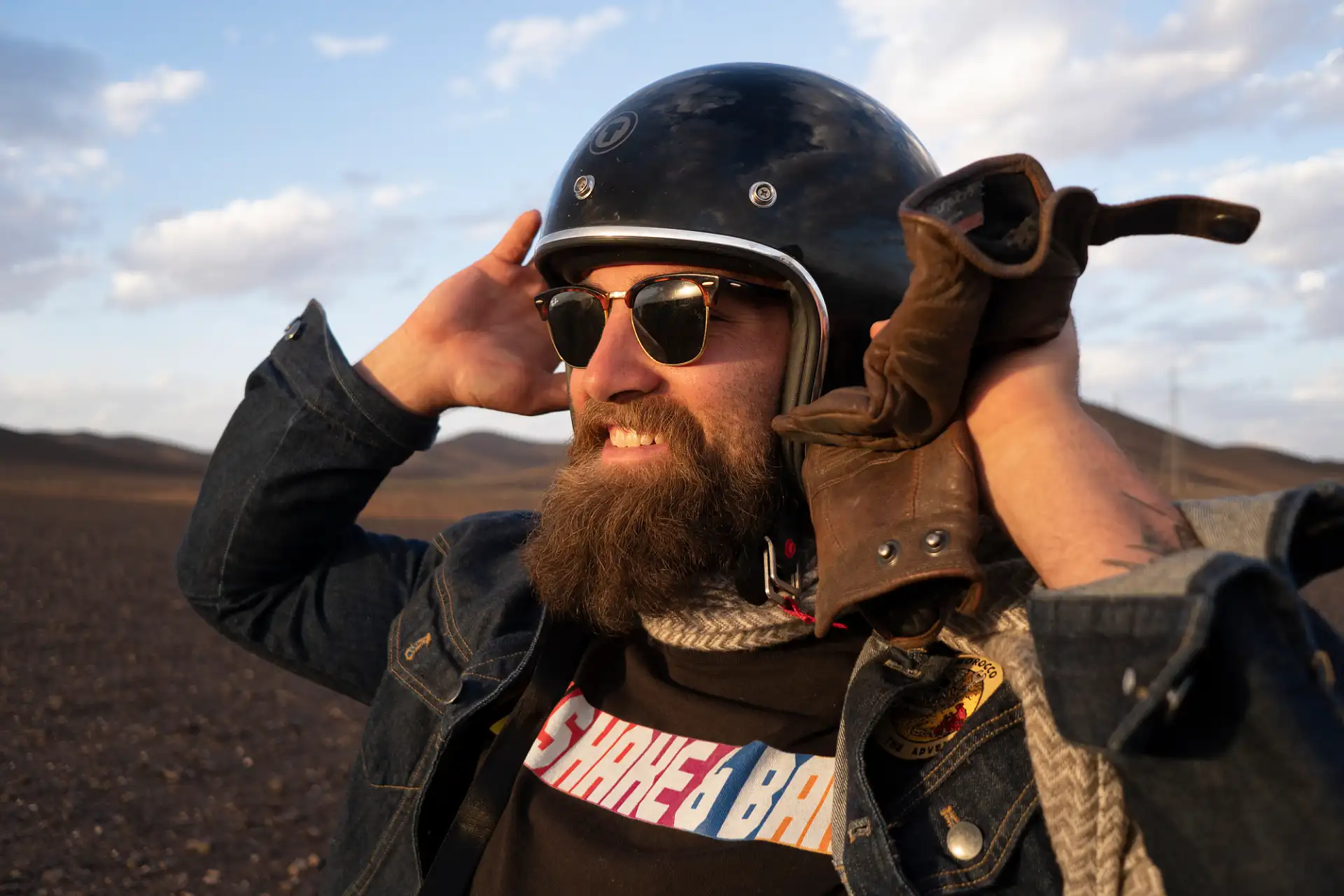 A rider adjusting his motorcycle helmet.