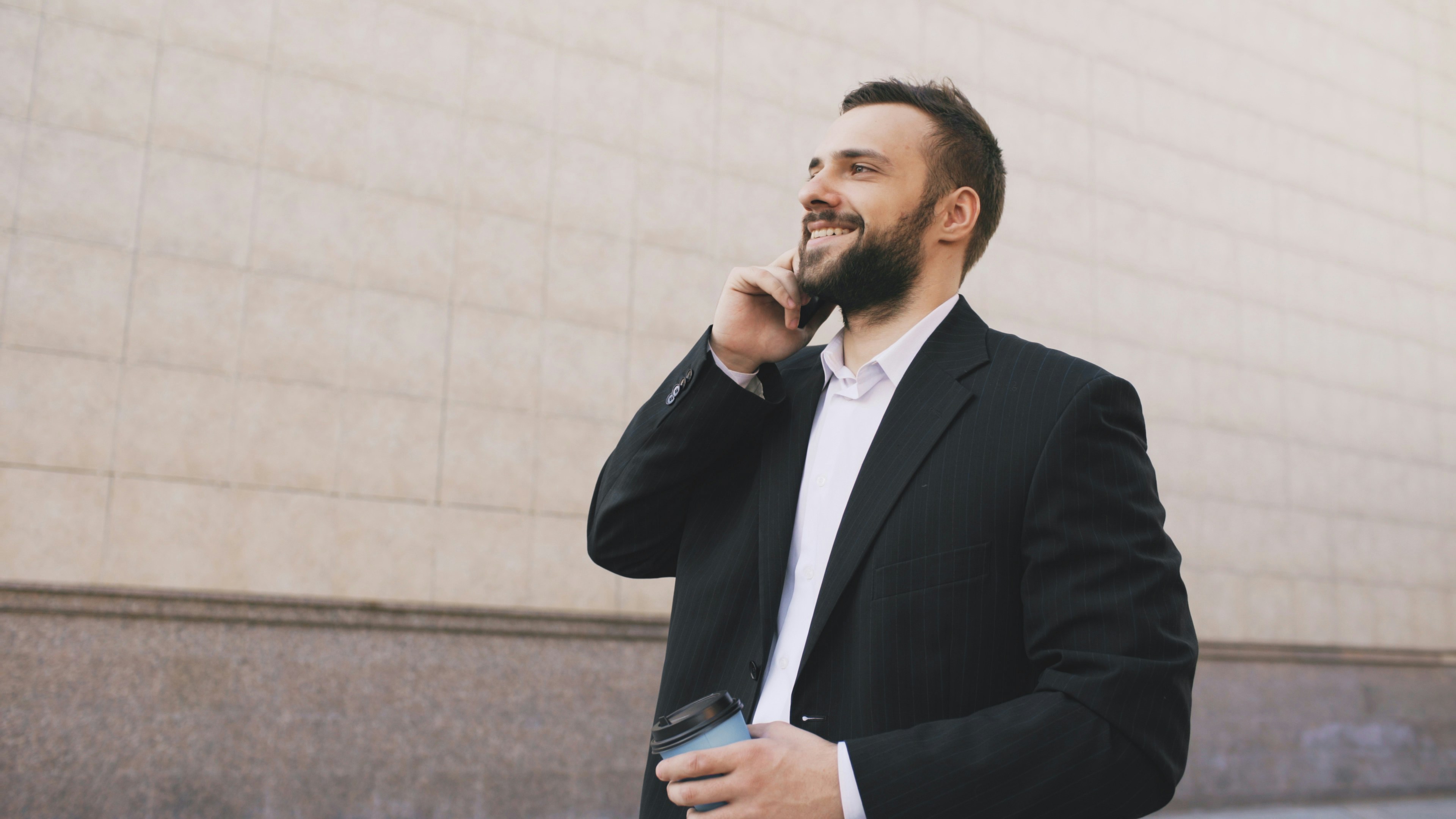 Man in suit talking on phone with coffee cup