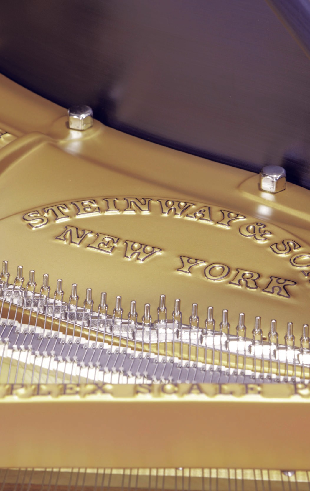 A close-up shot of the interior lid and golden plate of a restored Steinway & Sons grand piano, emphasizing the luxurious restoration.