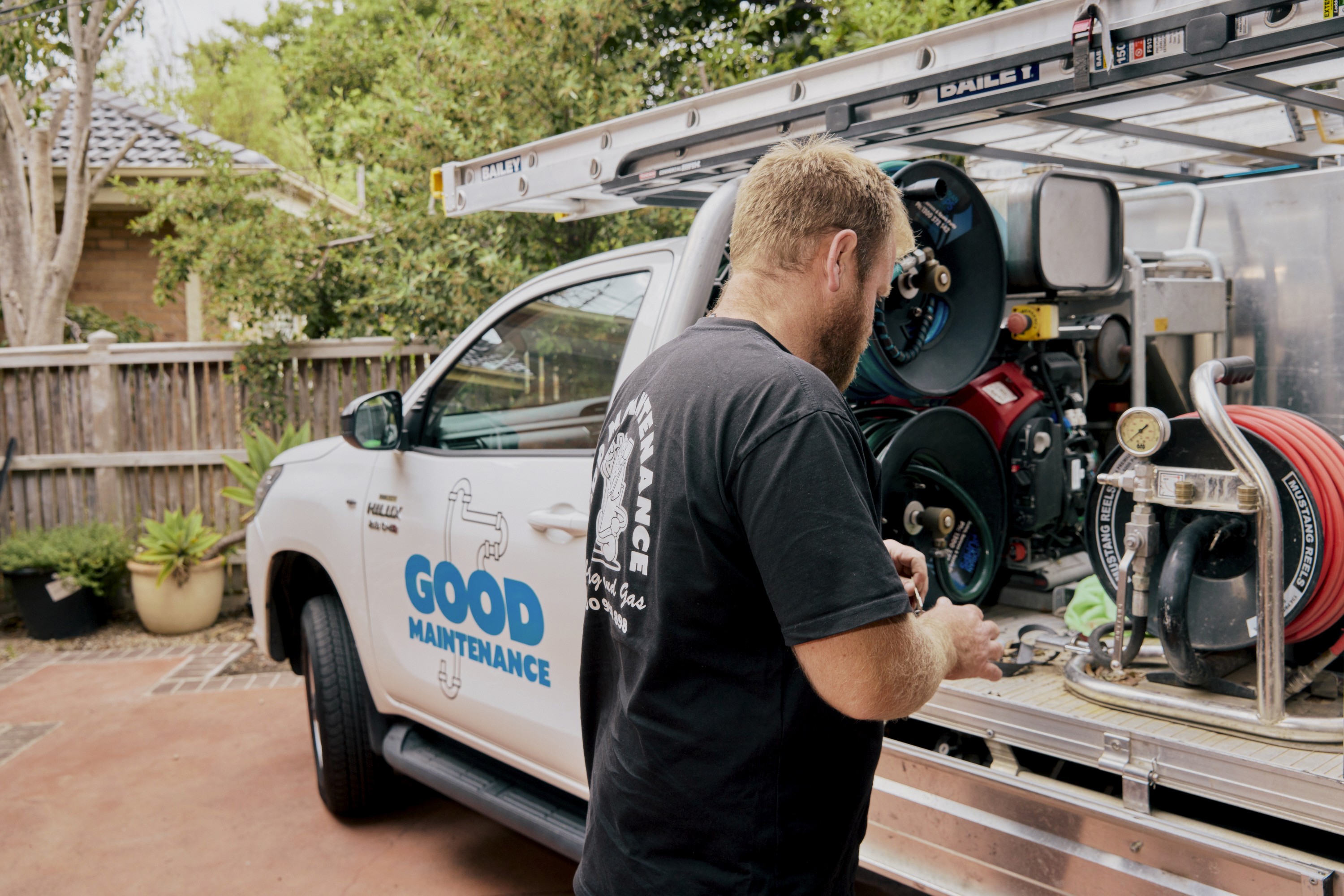 Good Maintenance Plumber threading a hose down a drain pipe at a residential property.