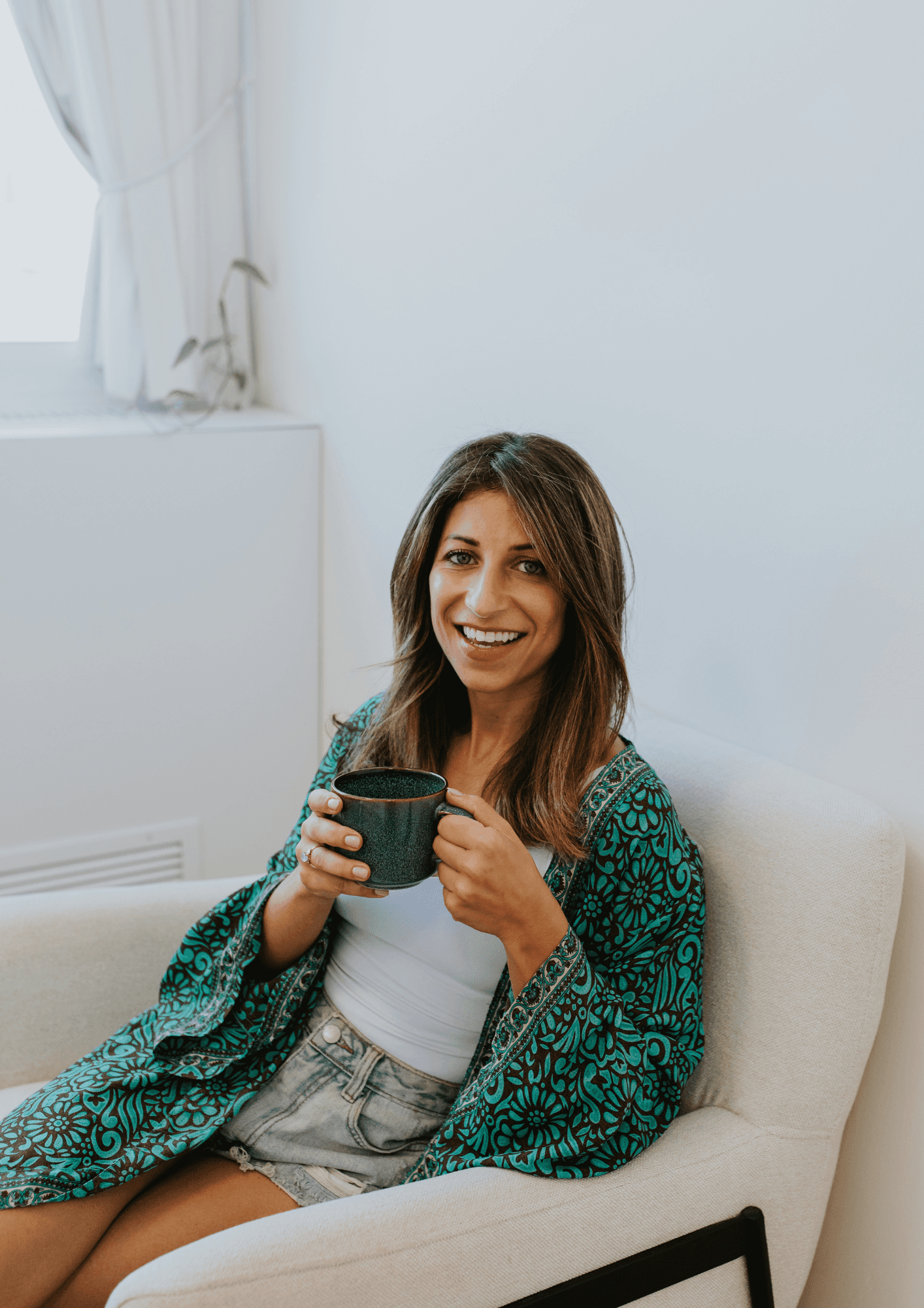A person with curly hair sits at a desk, working on a laptop in a cozy, well-lit environment.