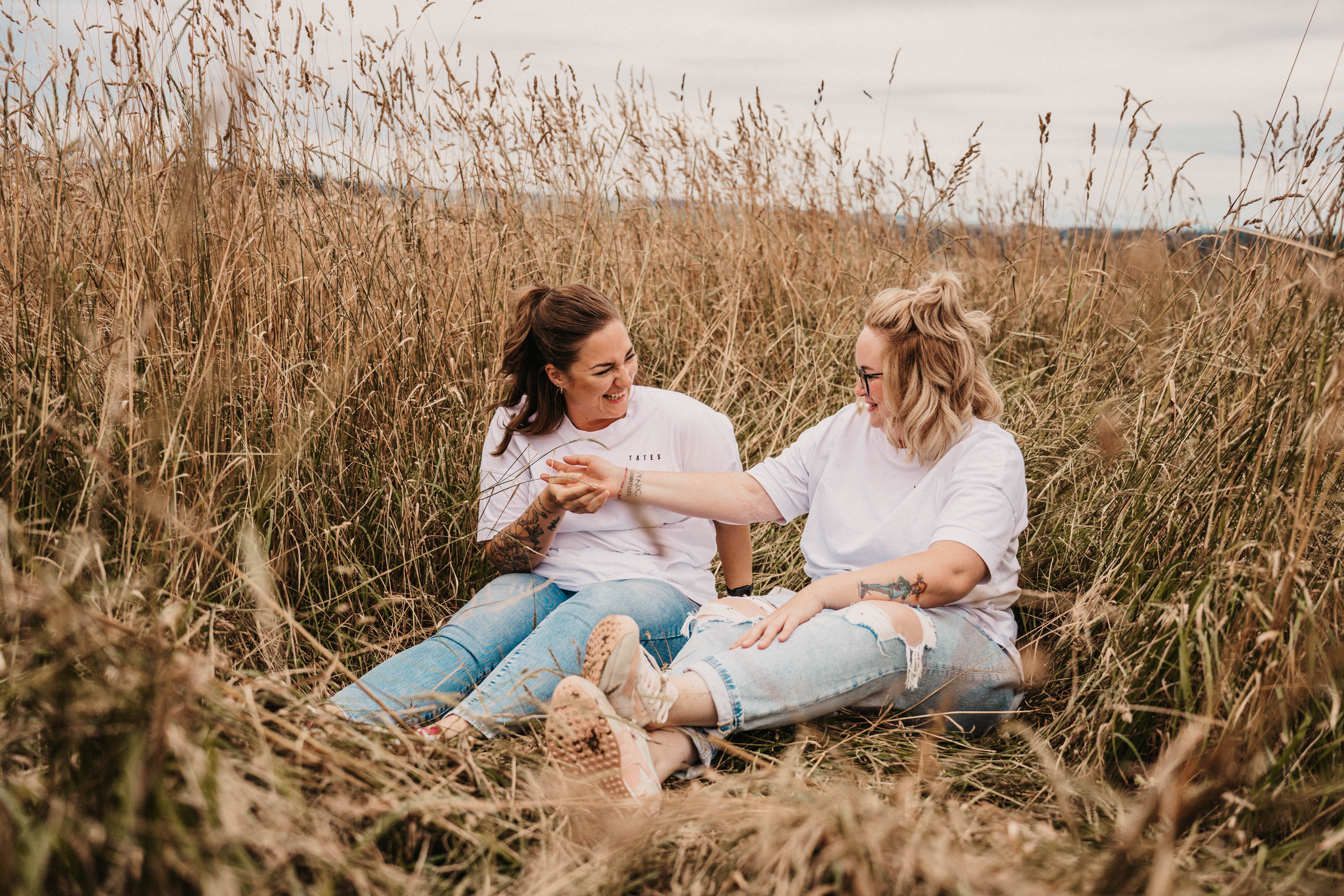 Zwei Freundinnnen sitzen in einem Feld und schauen sich an