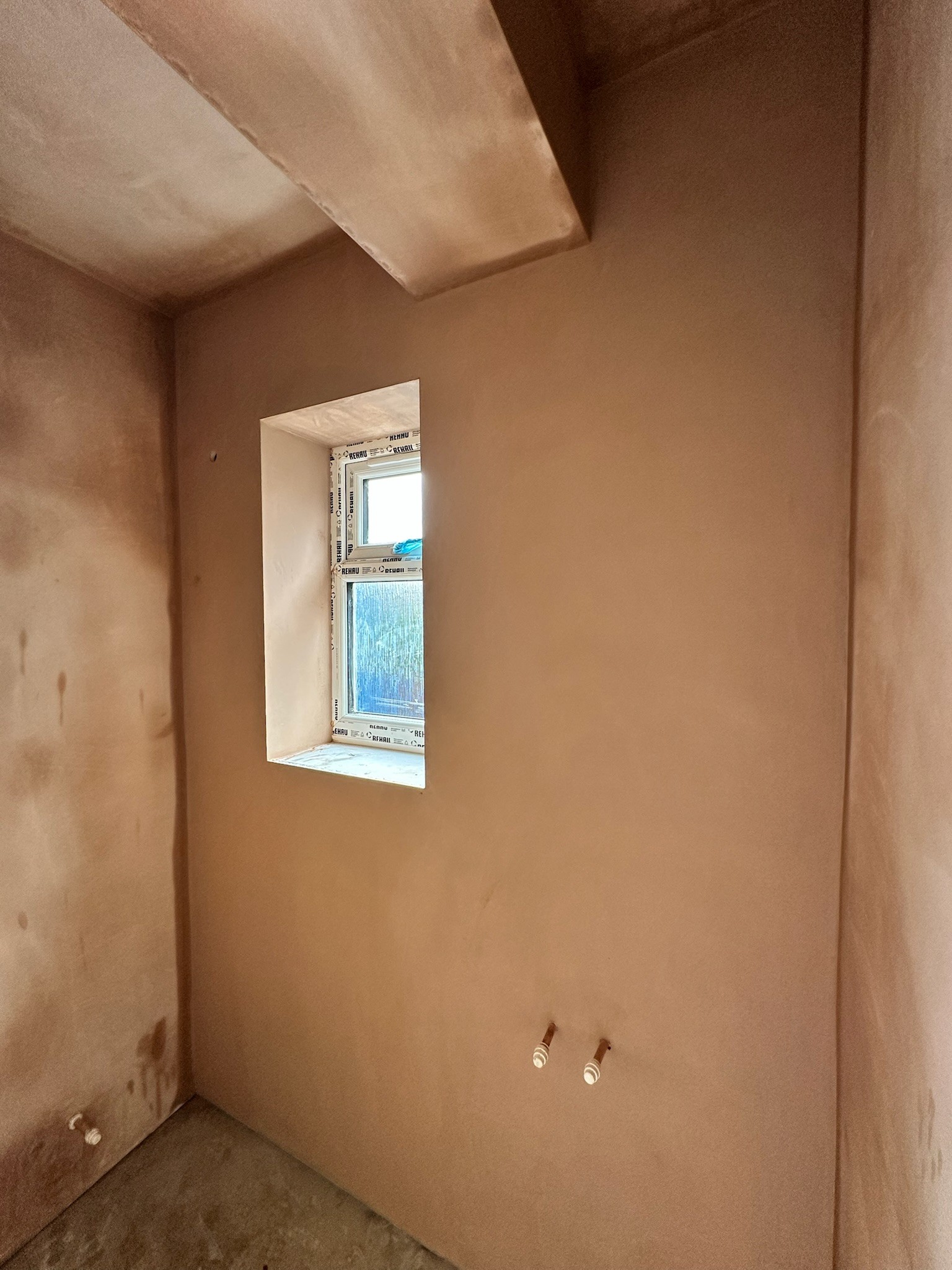 Plastered room showing window reveals and beam.