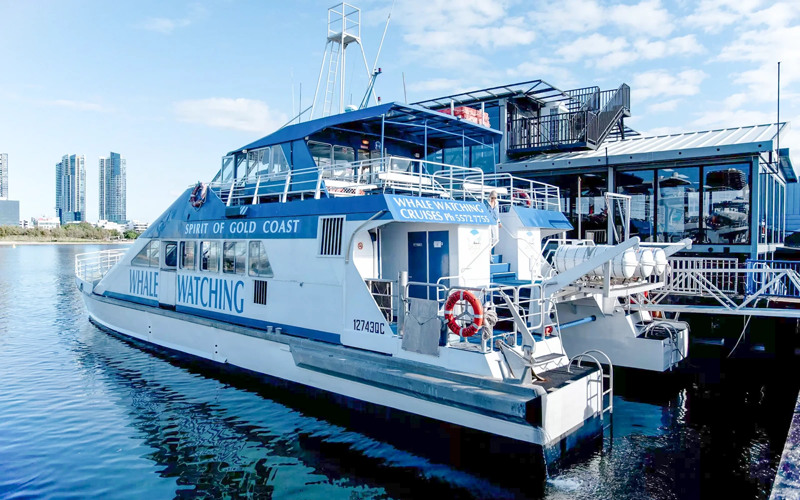 观鲸船“黄金海岸之魂”停泊在码头，背景是摩天大楼。