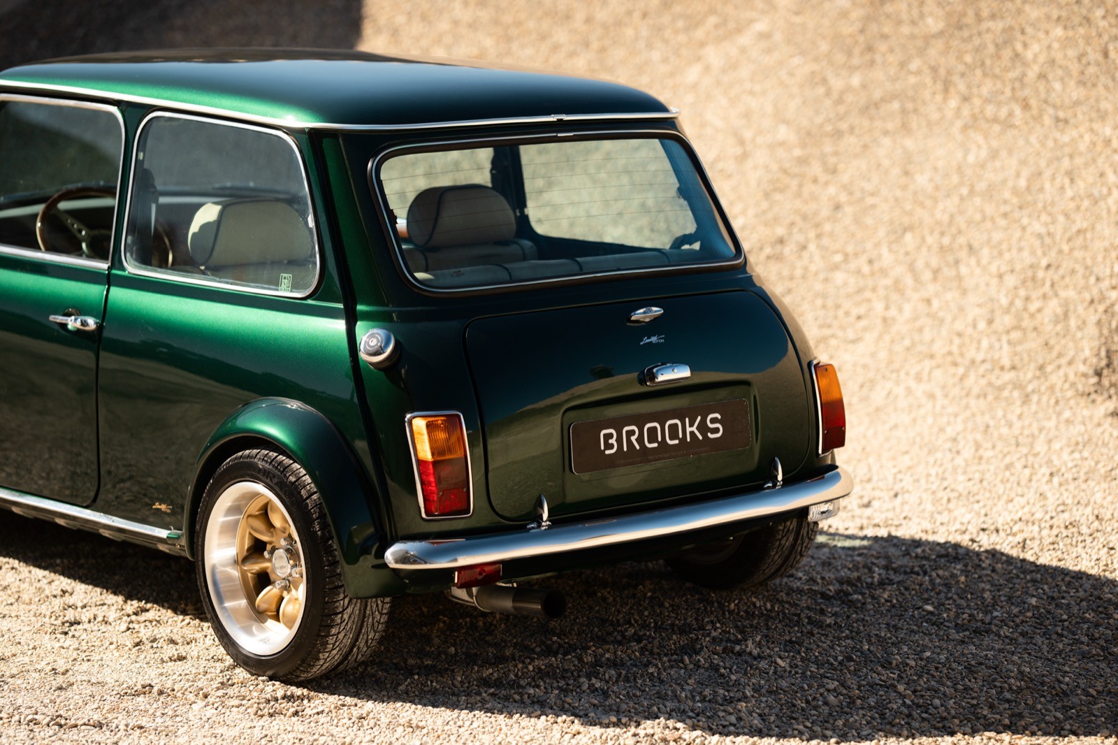 A small, green and black vehicle parked on a sandy surface, with a warm sunset lighting the scene.