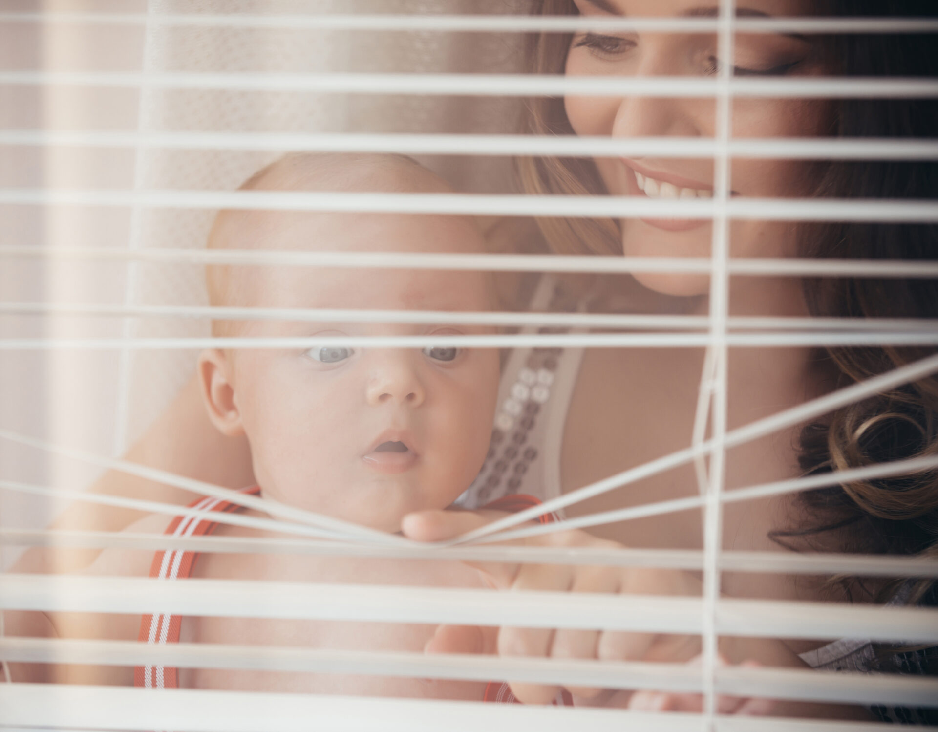 Baby son and mother open window blinds. Wholesale Blind Factory.