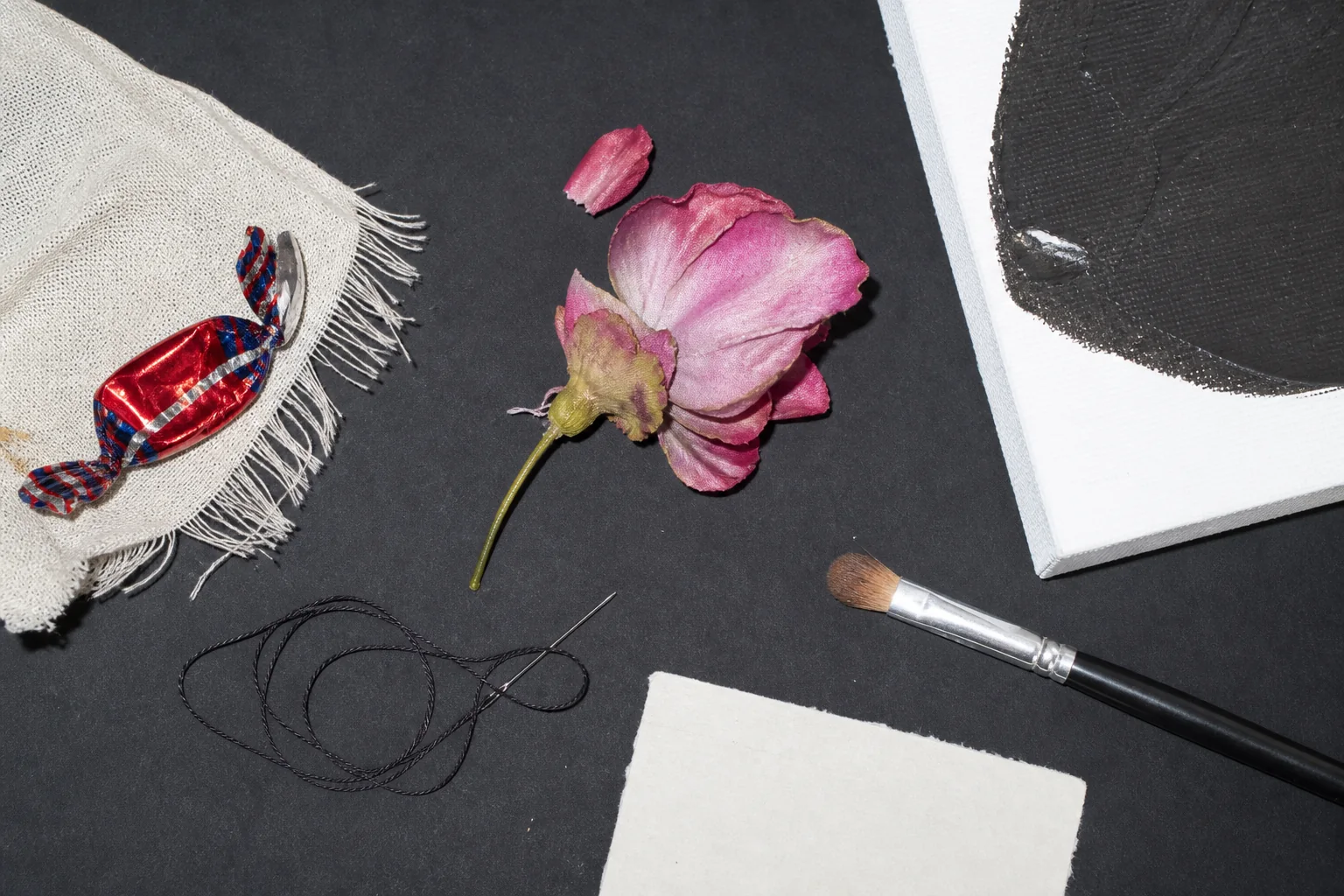 Repair table with candy shell, flower, paint chip, thread, brush, and archival tissue.