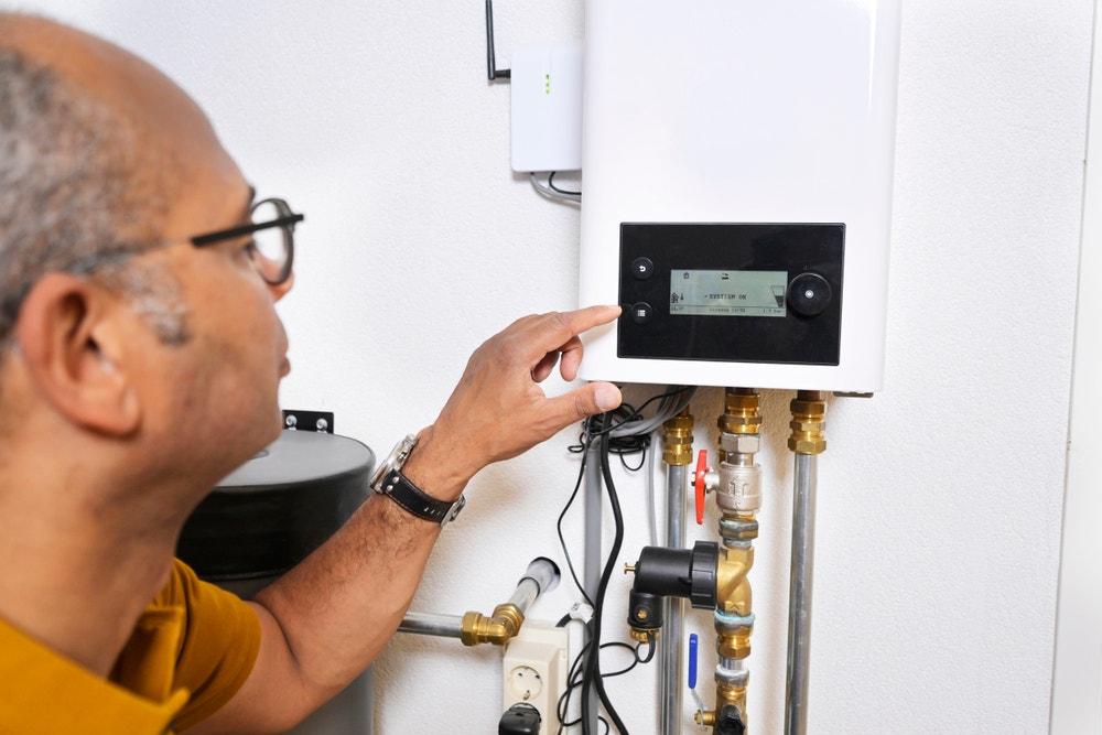 Heat pump engineer adjusting controller settings on a UK heating system — showing the type of controls review carried out to identify disabled weather compensation settings at handover.
