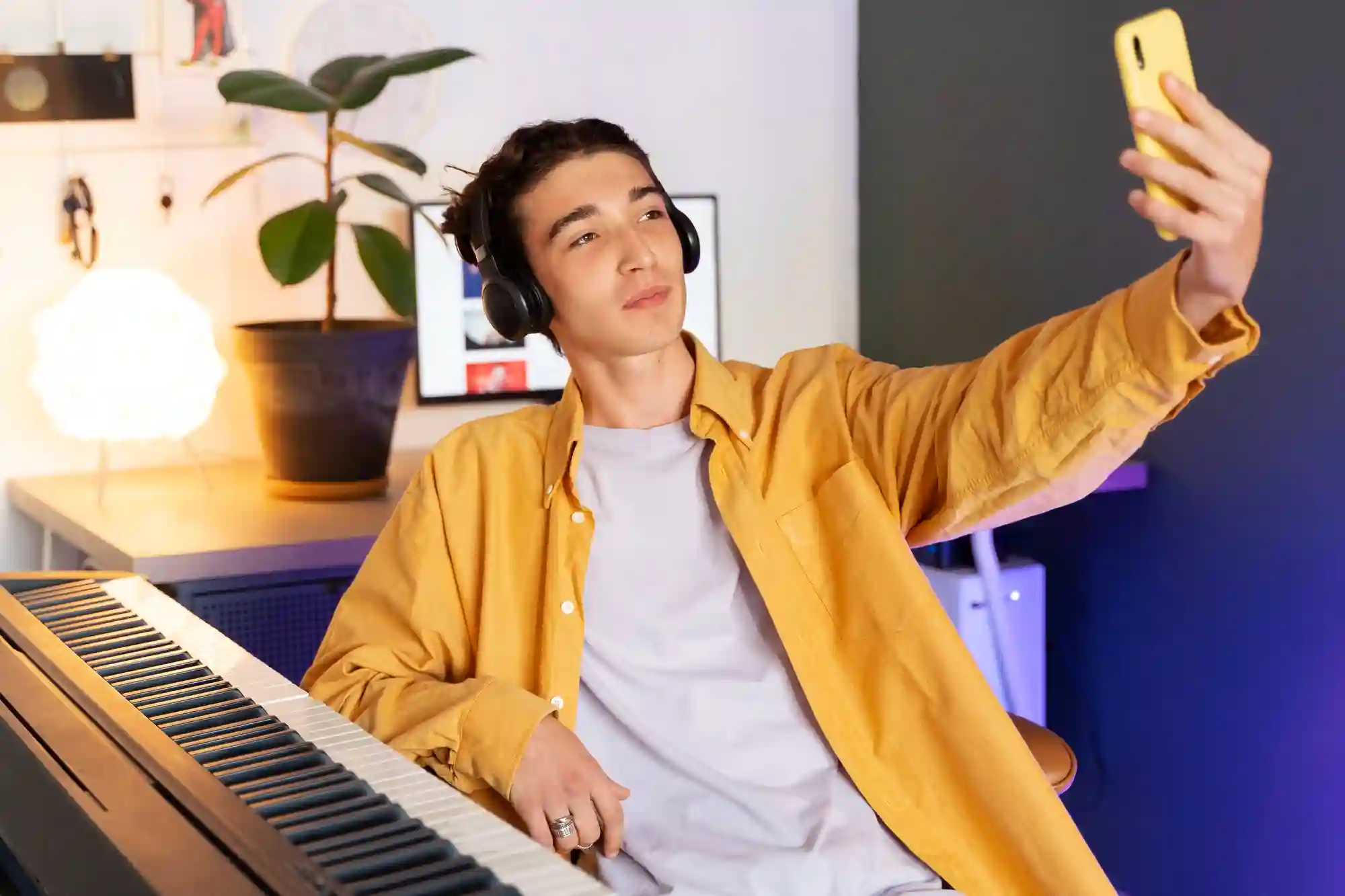 Musician in headphones recording a selfie video or live stream of his music session on a smartphone.