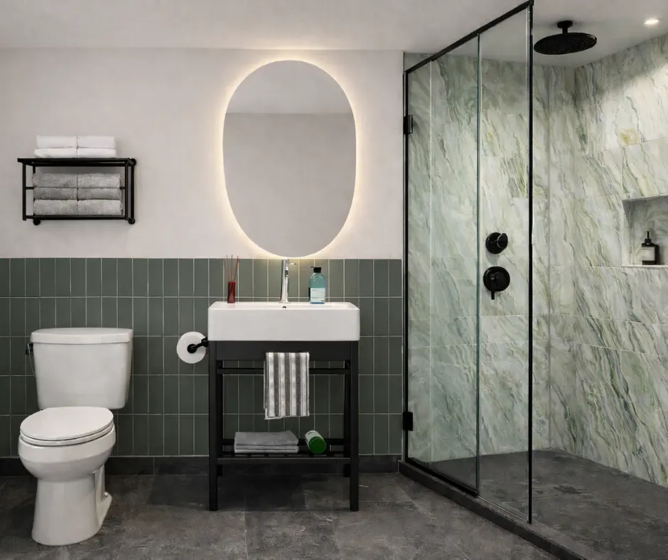Modern bathroom featuring a shower, sink with a mirror, and a toilet against a stylish green and gray backdrop.