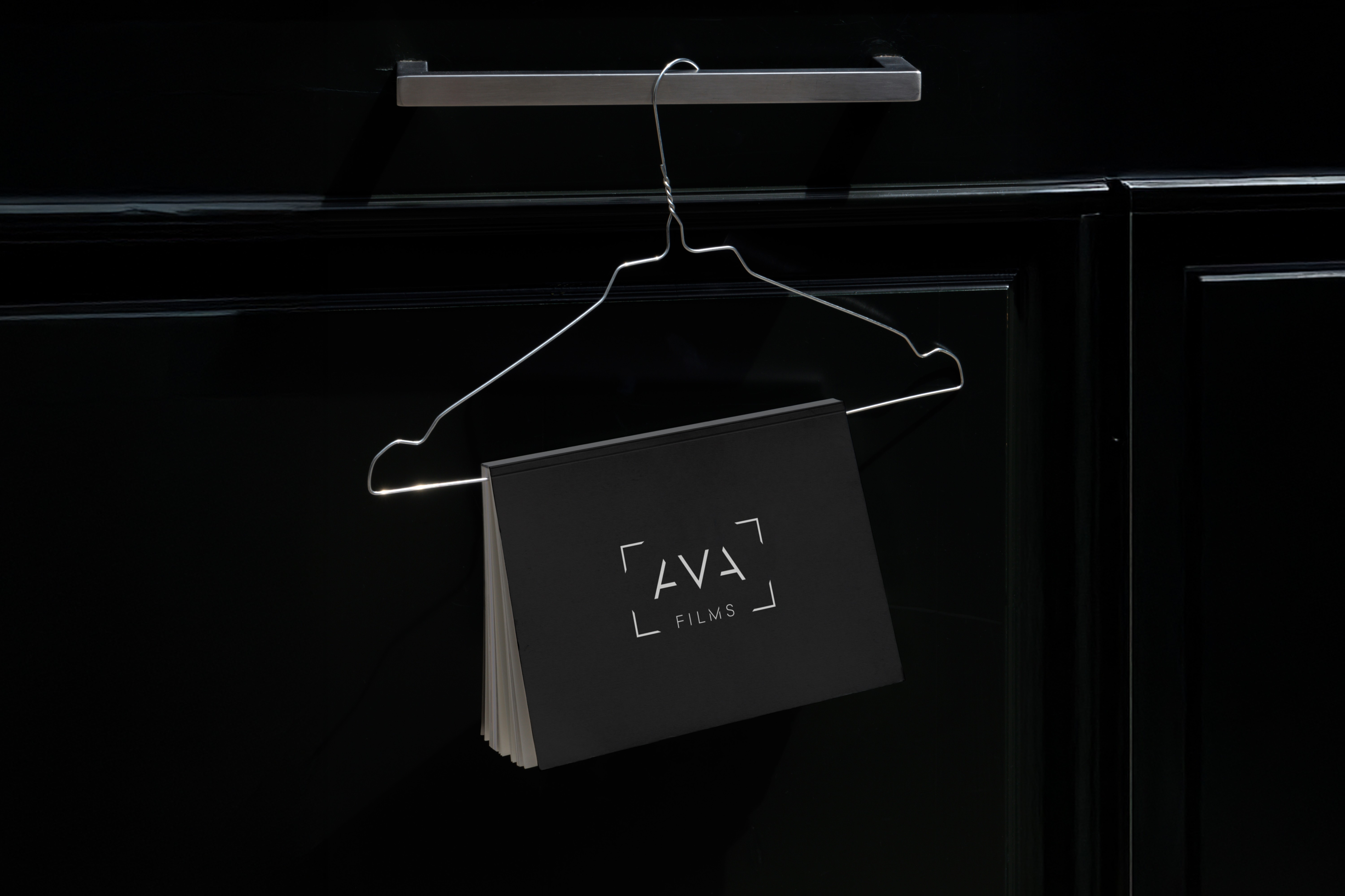 AVA Films shopping bag hanging on a sleek black hanger, representing a sophisticated branding touch for a premium video production company.