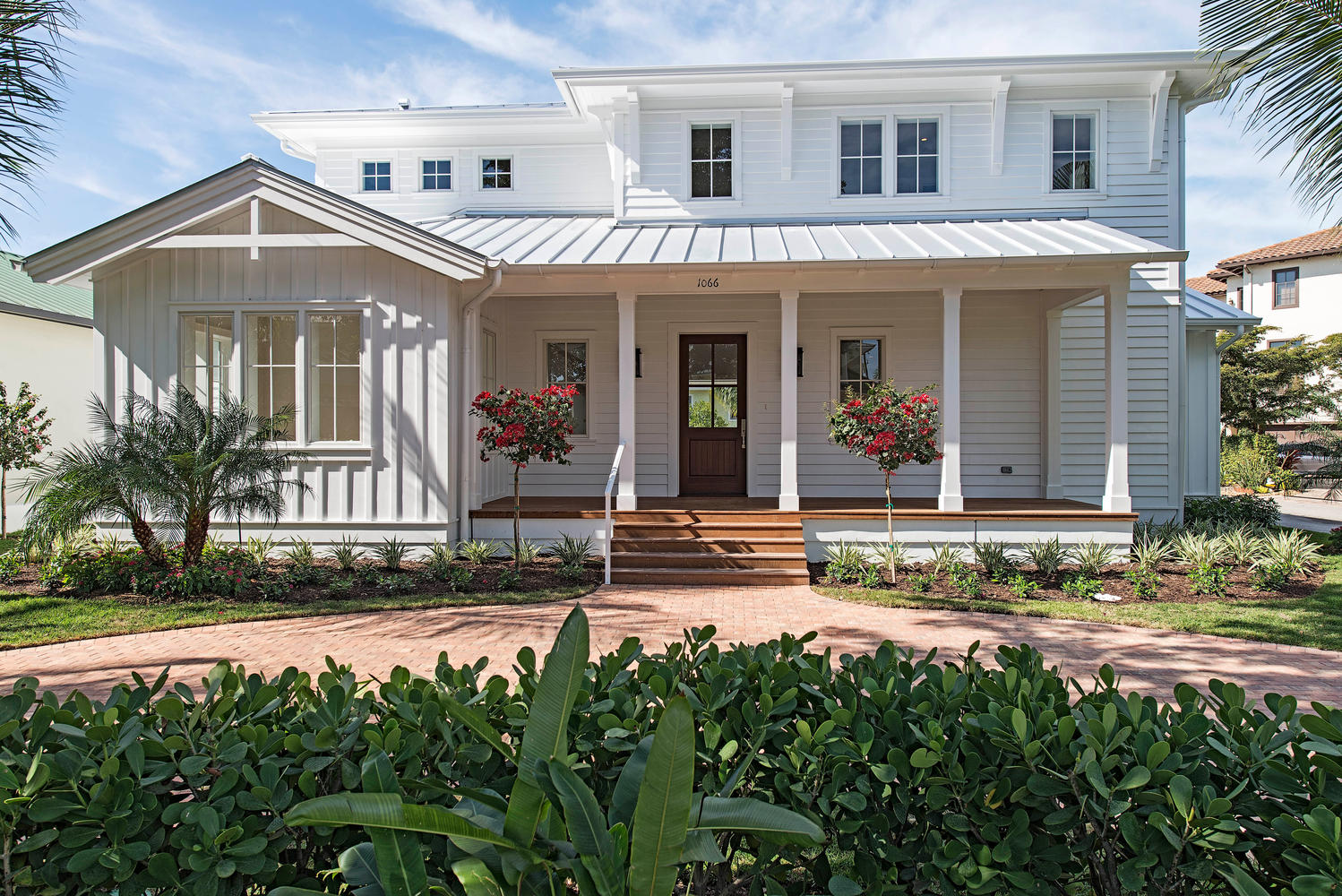 a classic white home with columns on the front porch and dense brush in the foreground