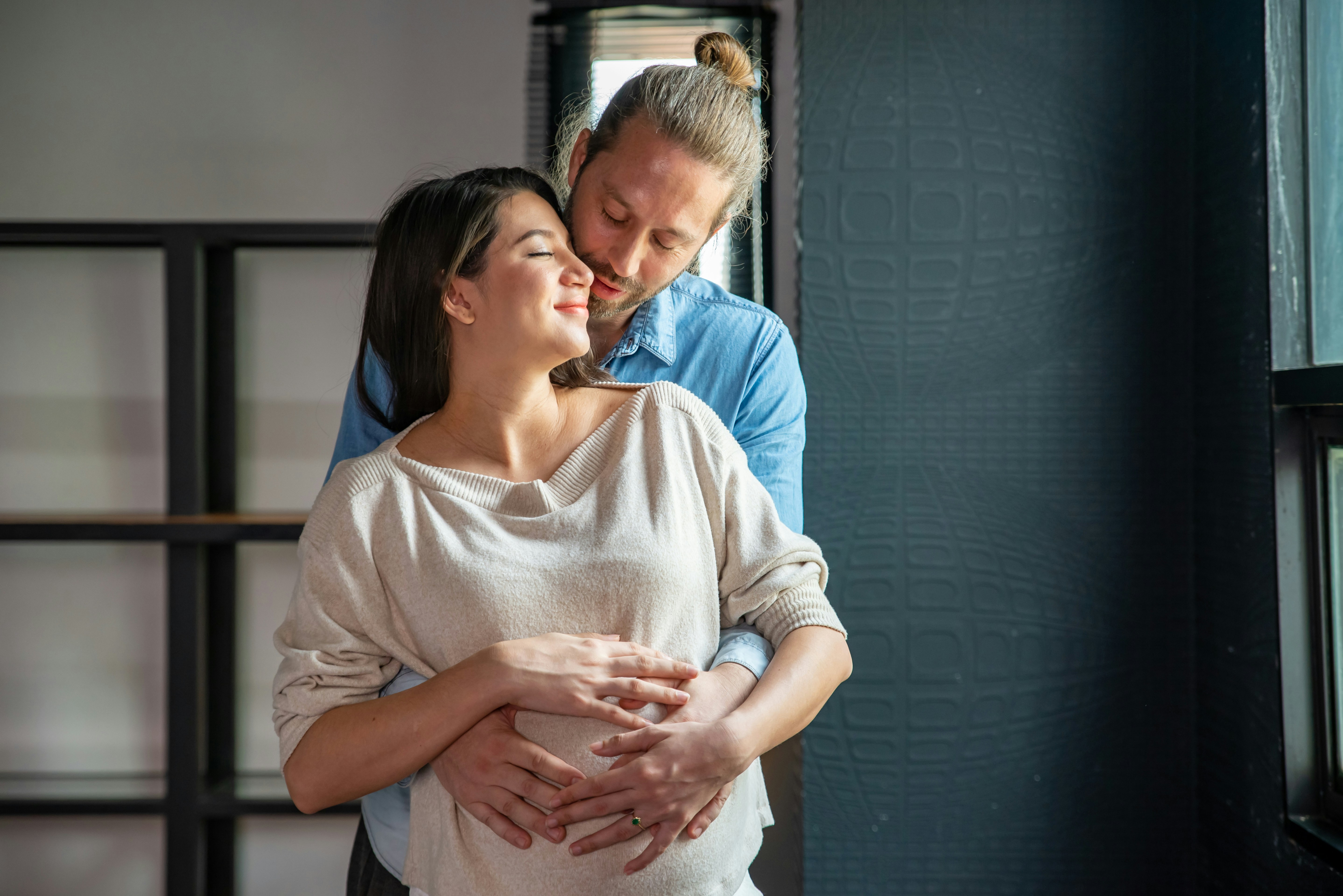 husband wraps arms around pregnant wife