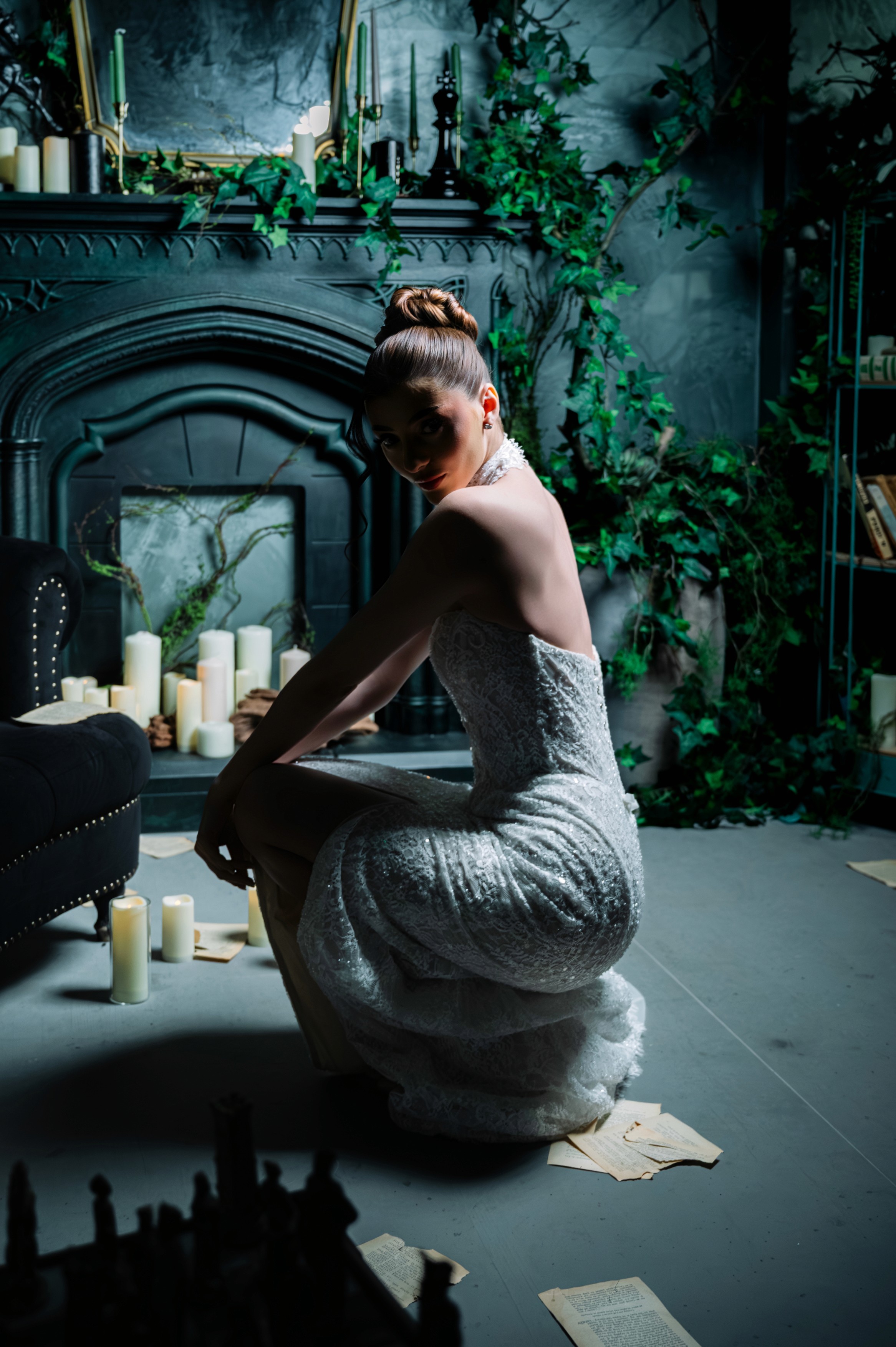 Mireasă așezată lângă lumânări într-un decor dramatic cu șemineu, fotografie bridal în București