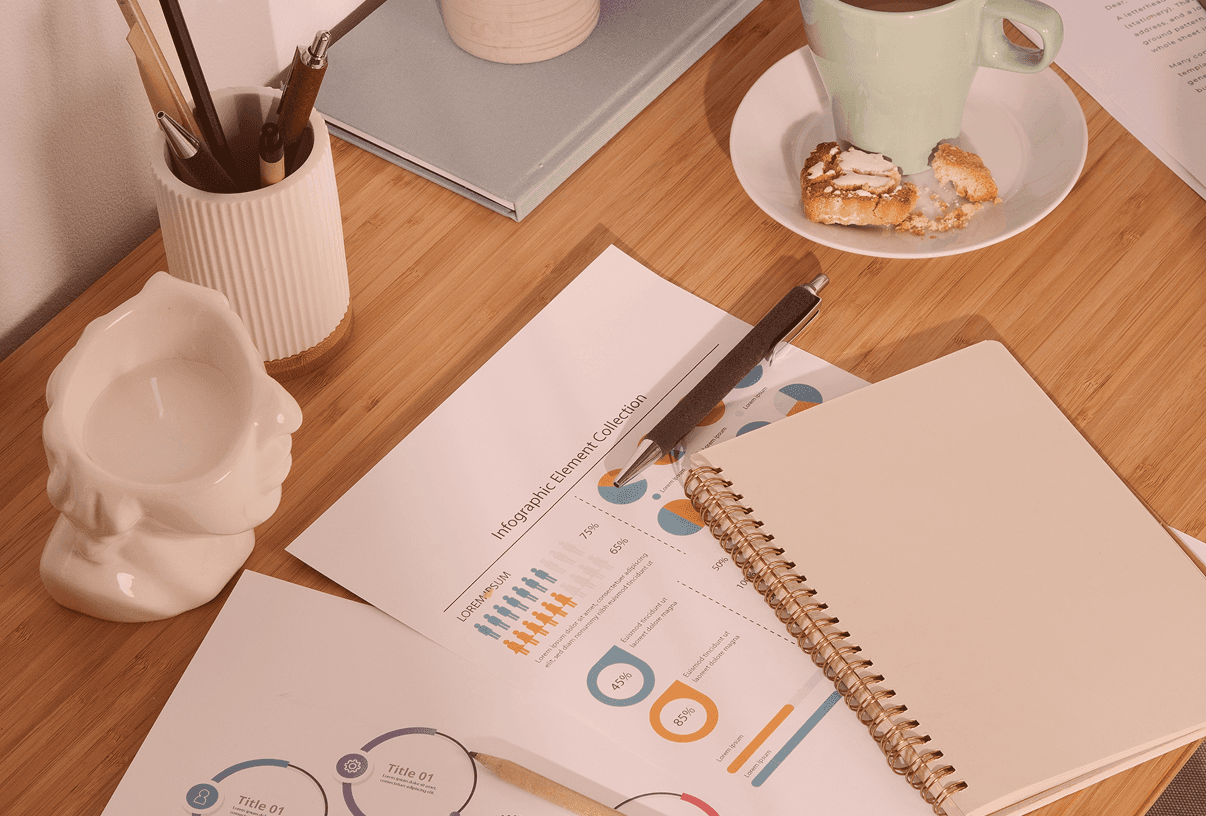 A workspace featuring marketing infographic reports with data charts, a spiral notebook, and a pen on a wooden desk—representing campaign performance analysis and strategic planning.