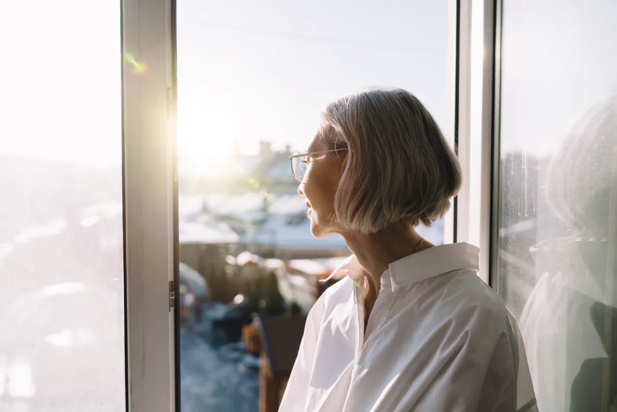 grey haired woman looking out of window