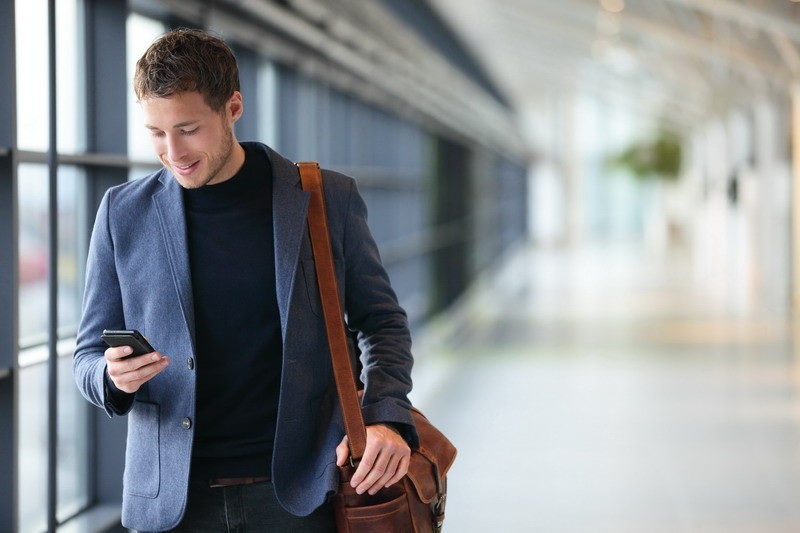 Man on smart phone – young business man in airport