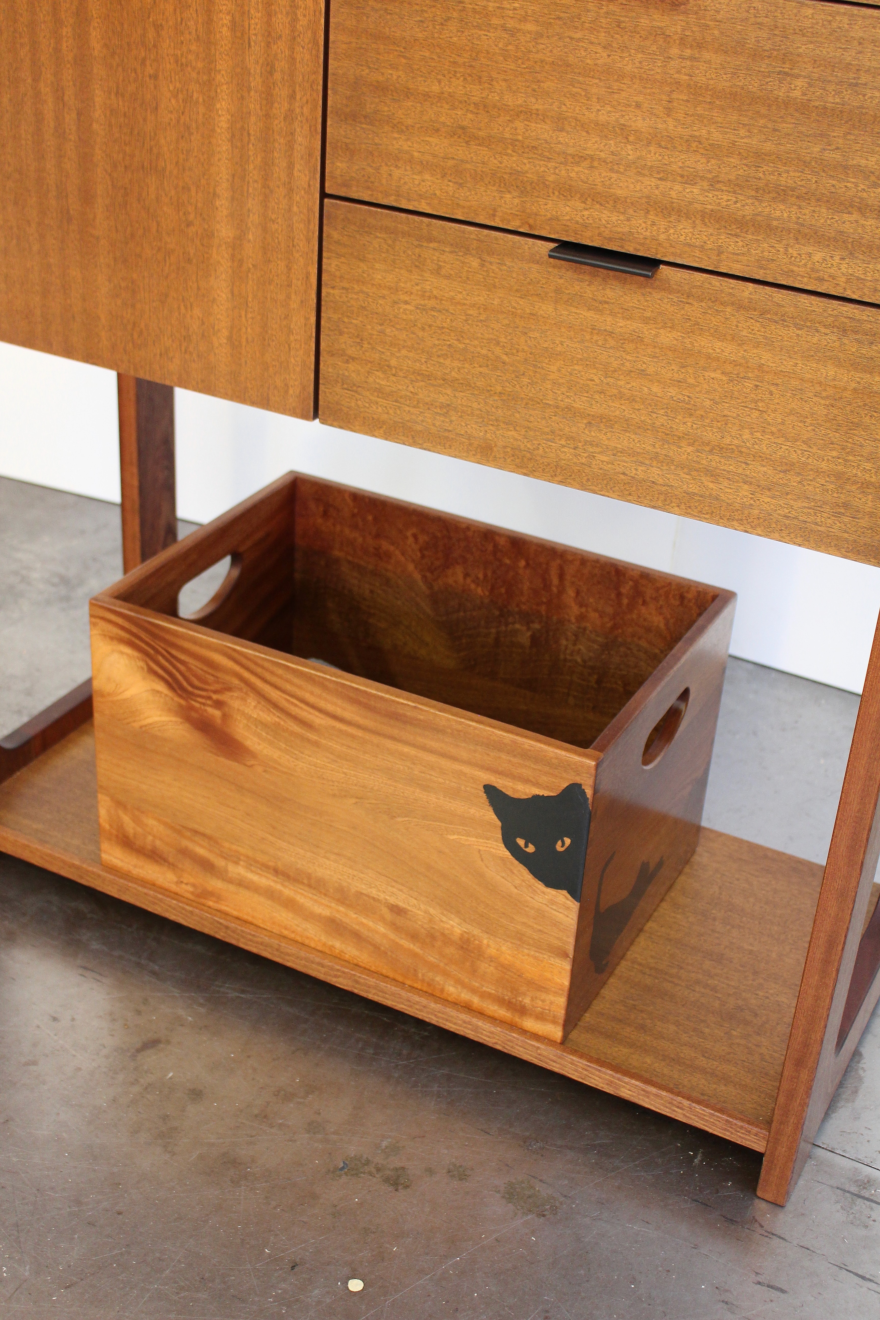 Detail of chifferobe base with children’s wooden toy box with black cats painted on it.