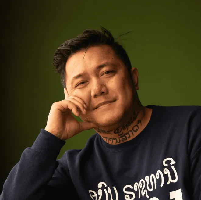 Smiling man resting his chin on his hand.
