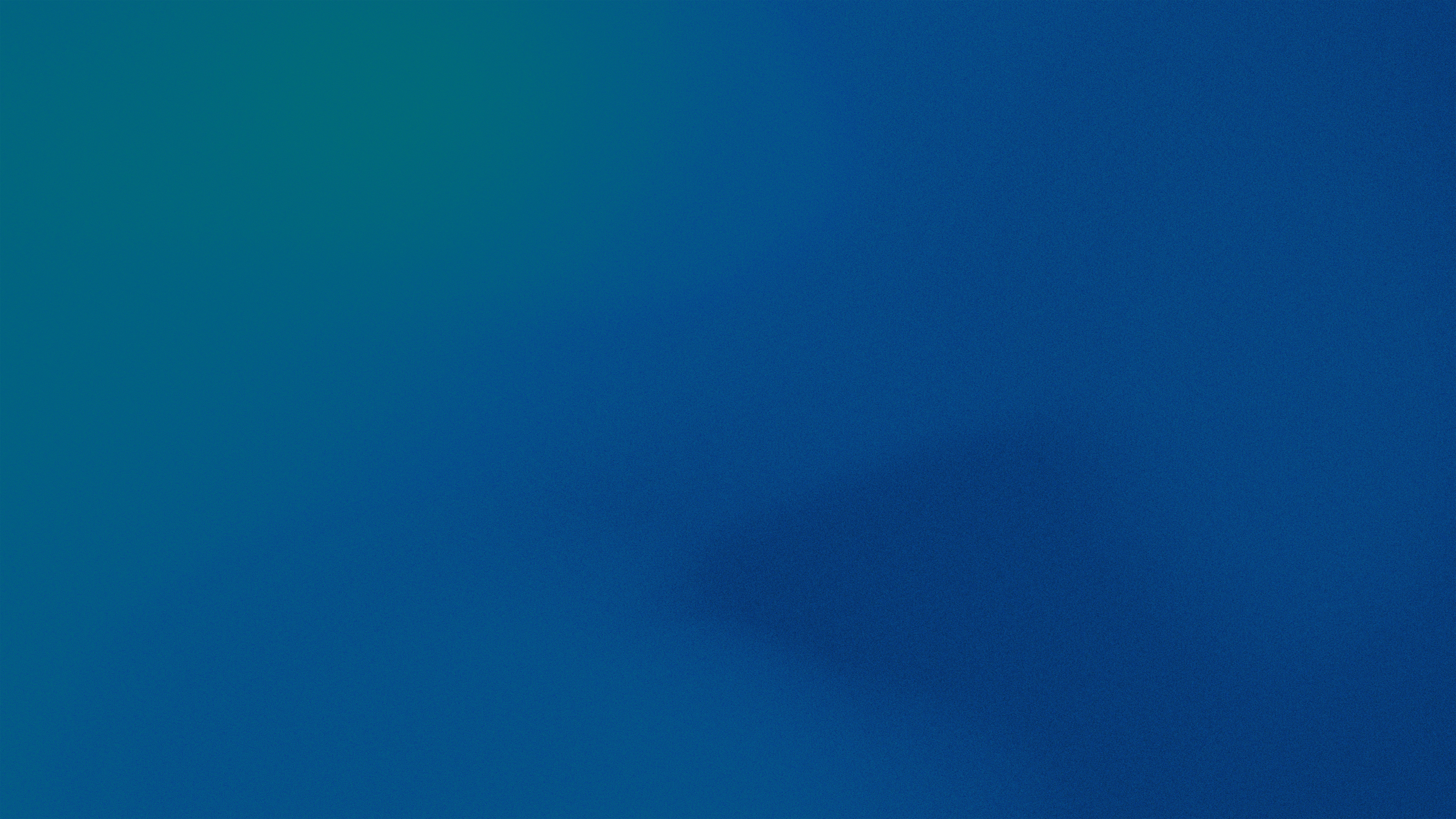 A man stands while two people sit at a table in an office setting, smiling and engaged in conversation. The mood is friendly and collaborative.