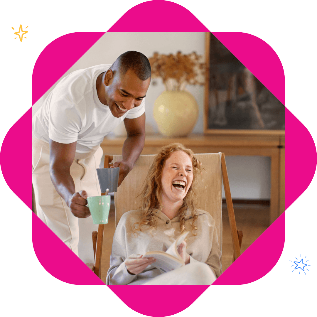 Man serving coffee to a laughing woman in a chair. They are enjoying a relaxing morning.