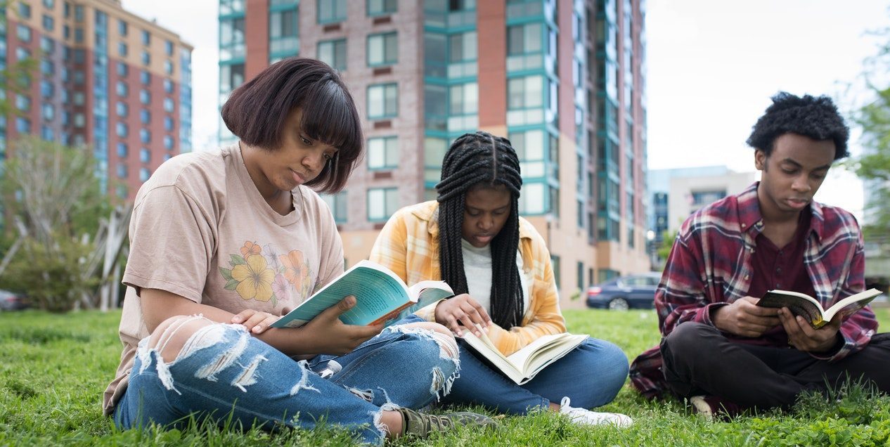 Three young people reading together on the grass
