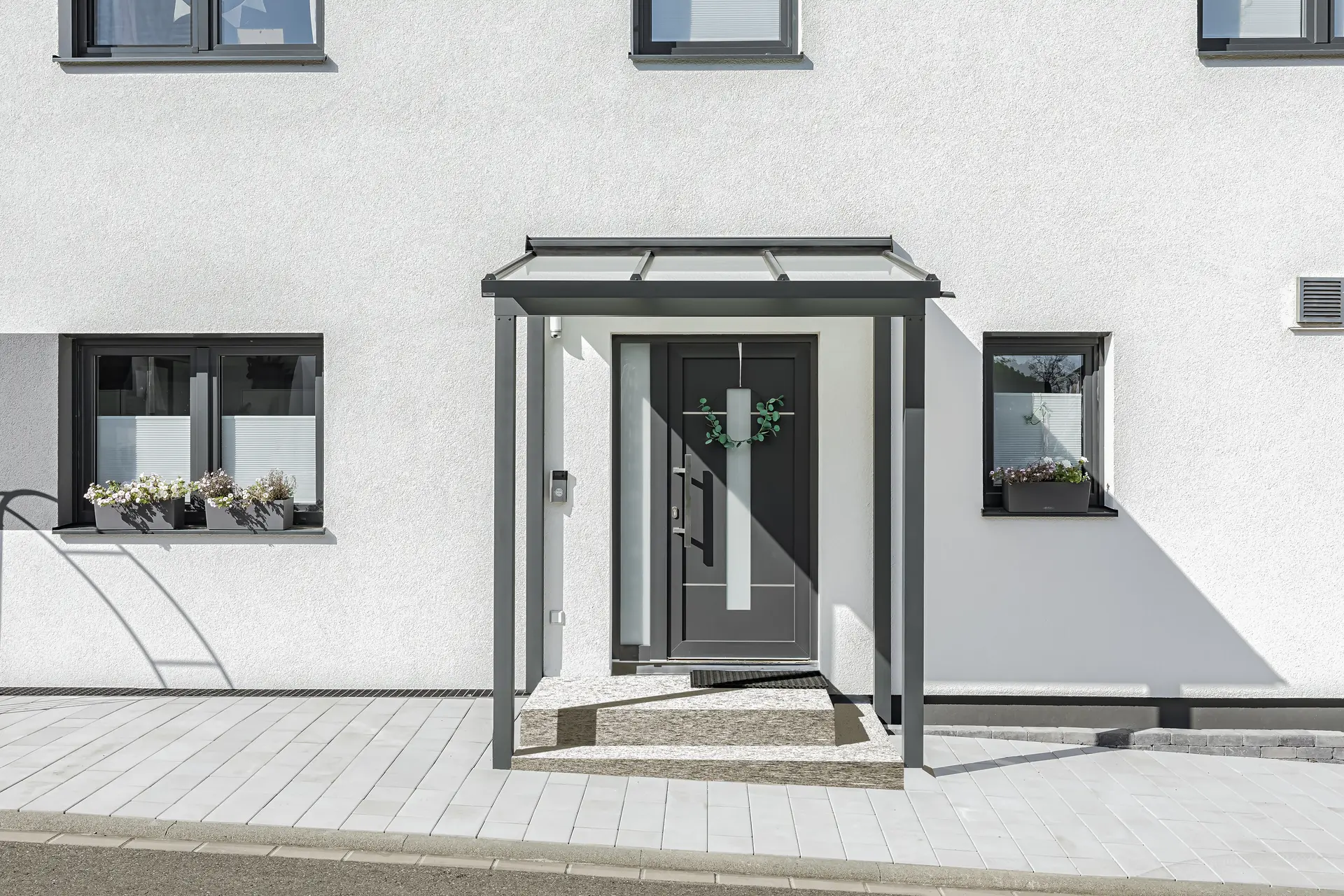 Vordach von Landauer aus dem System belanda auf 4 Stützen gestellt mit perfektem harmonischen Rahmen für die Haustüre