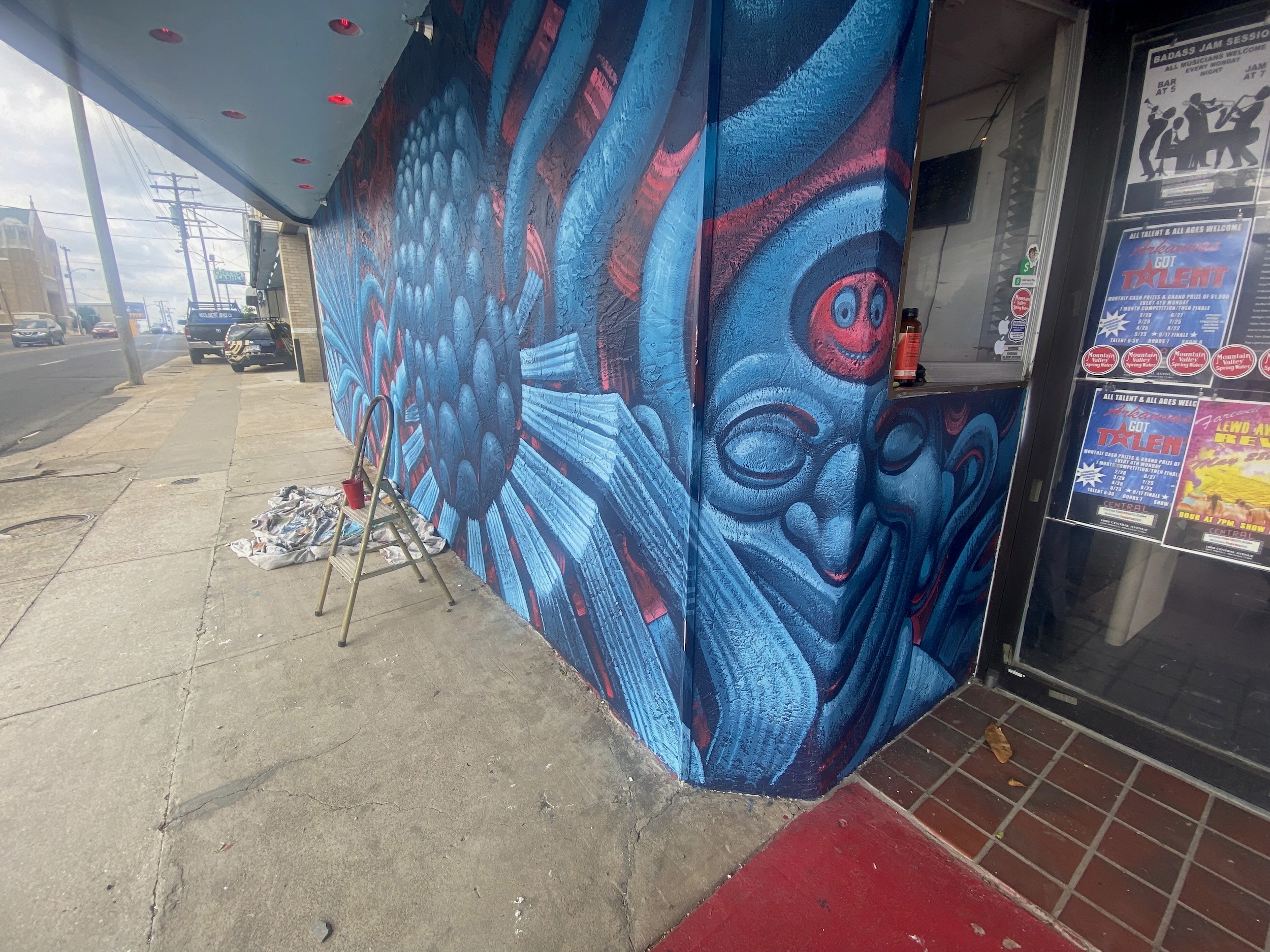 A blue face and petals wrap the theatre's entrance wall beside posters.