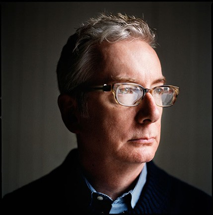 A photo of a man wearing glasses and a blue shirt.
