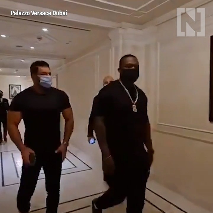 Black-and-white party photo of a smiling man in a check blazer among a crowd.