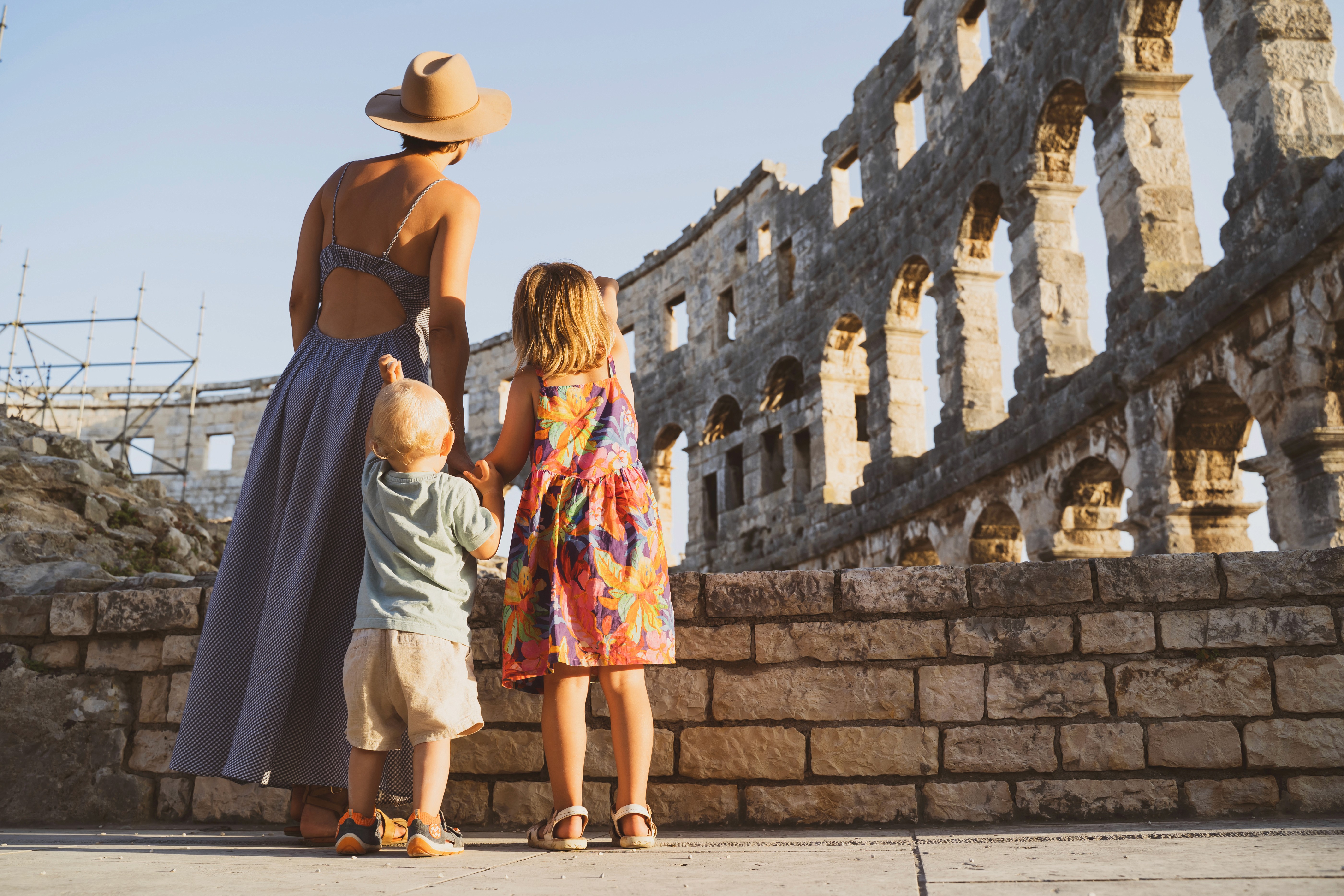 Mutter erkundet mit zwei Kindern ein antikes Amphitheater während einer Familienreise.