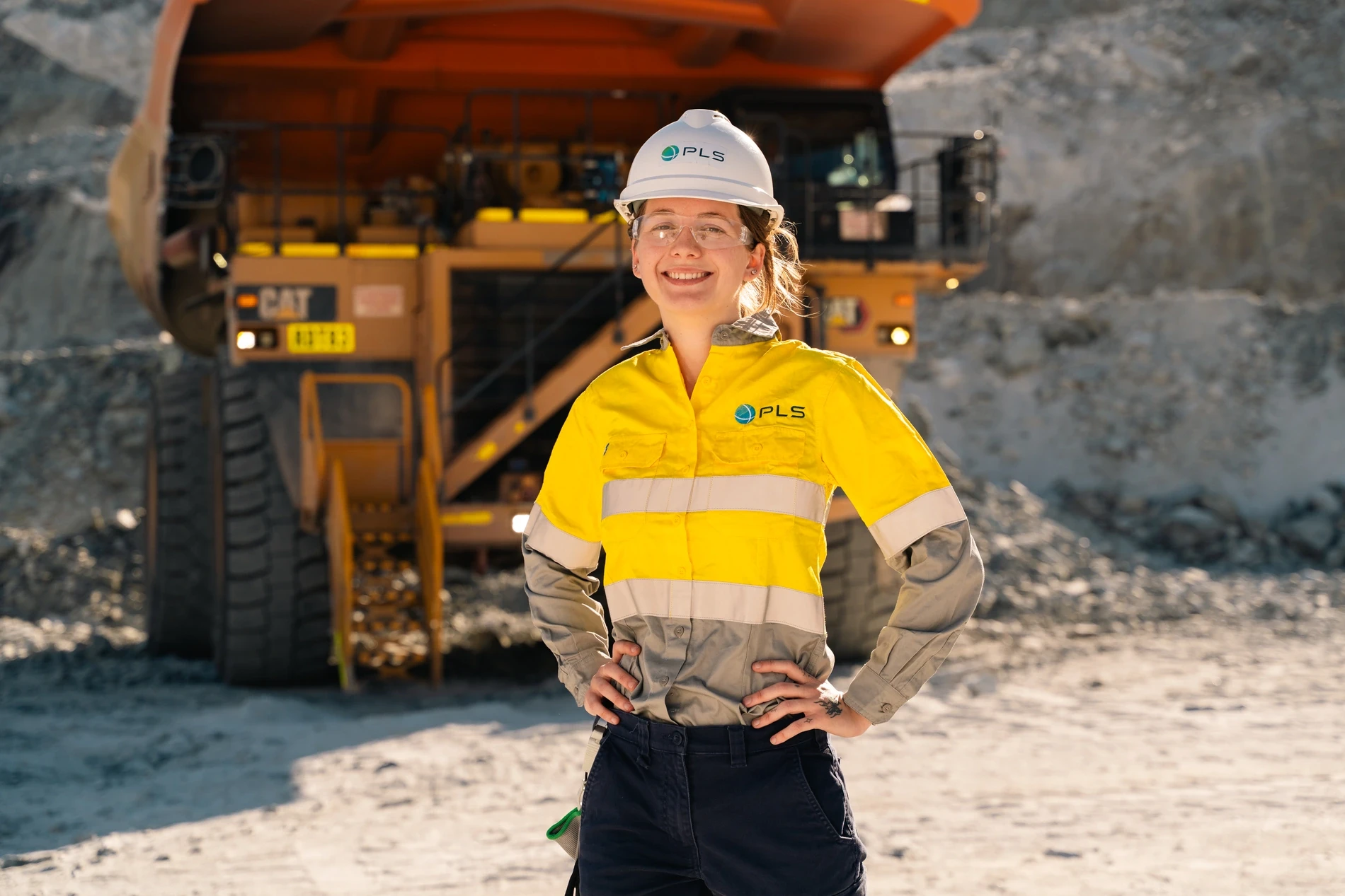 Worker in high-visibility uniform in front of a haul truck at Pilgangoora, Pilbara Minerals, Western Australia