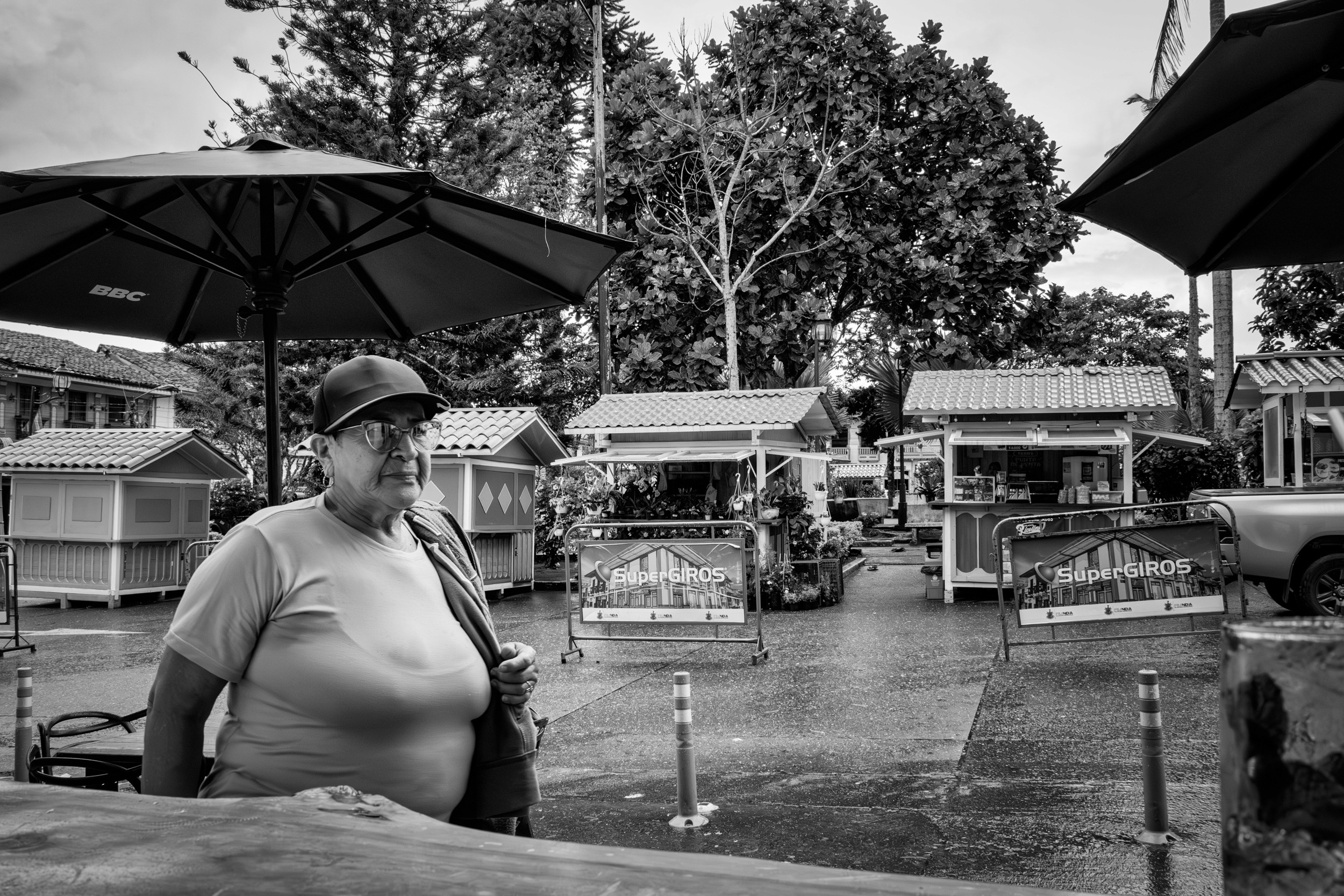 Rainy street scene with people passing by a bar window.