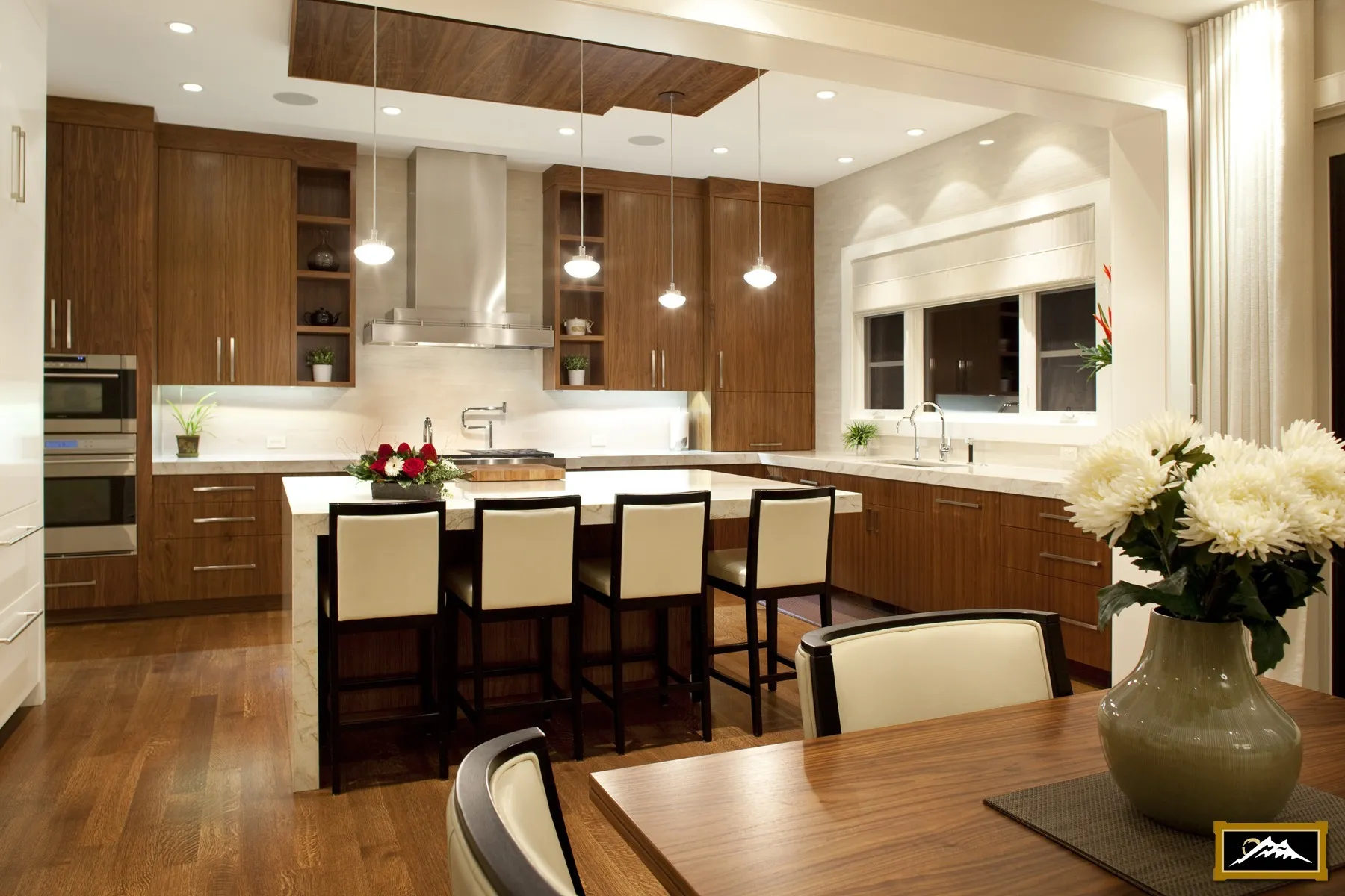 Image of large kitchen with mid-toned millwork and four island chairs.