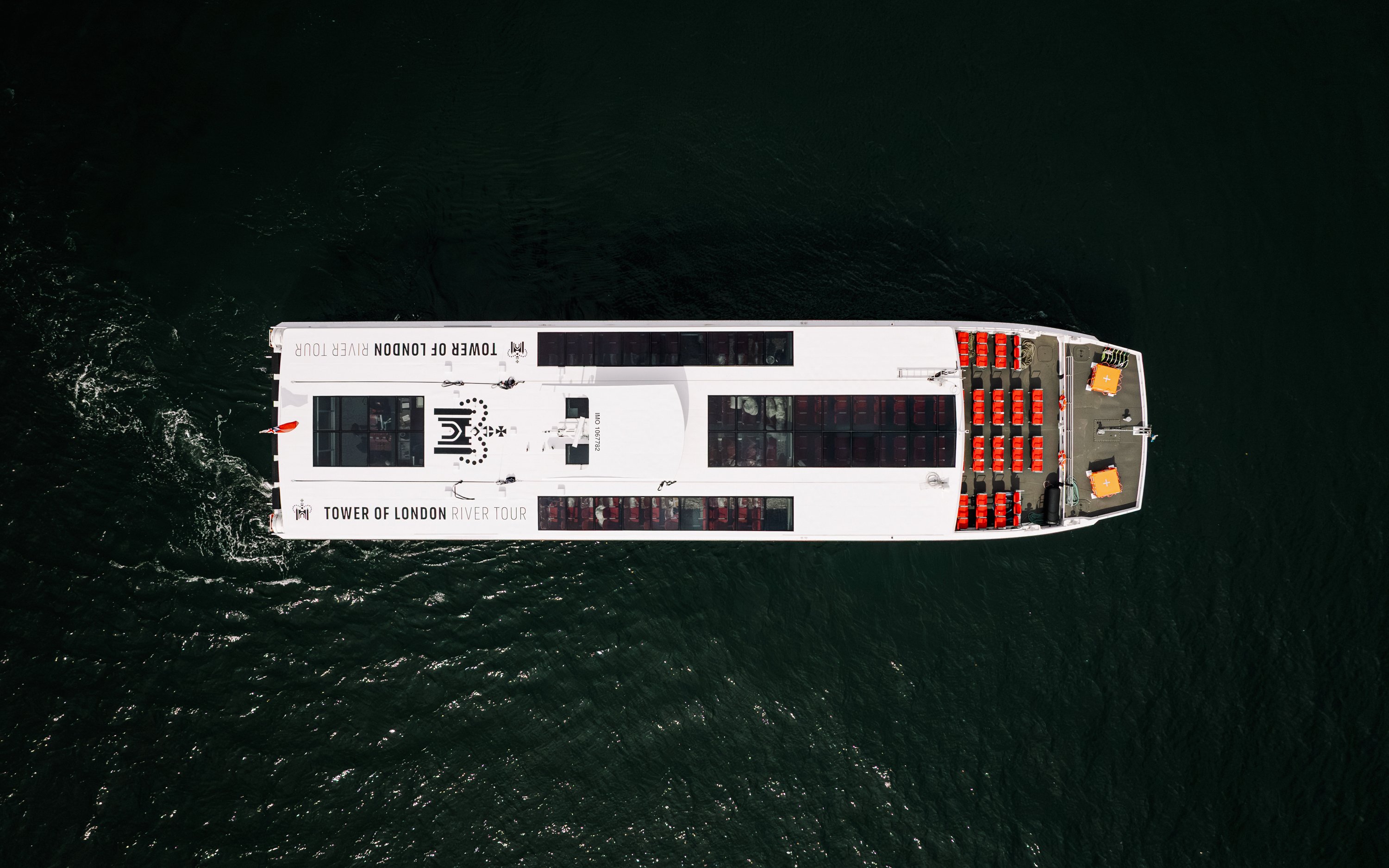 Vista aérea de un barco turístico en el río Támesis, frente a la Torre de Londres.