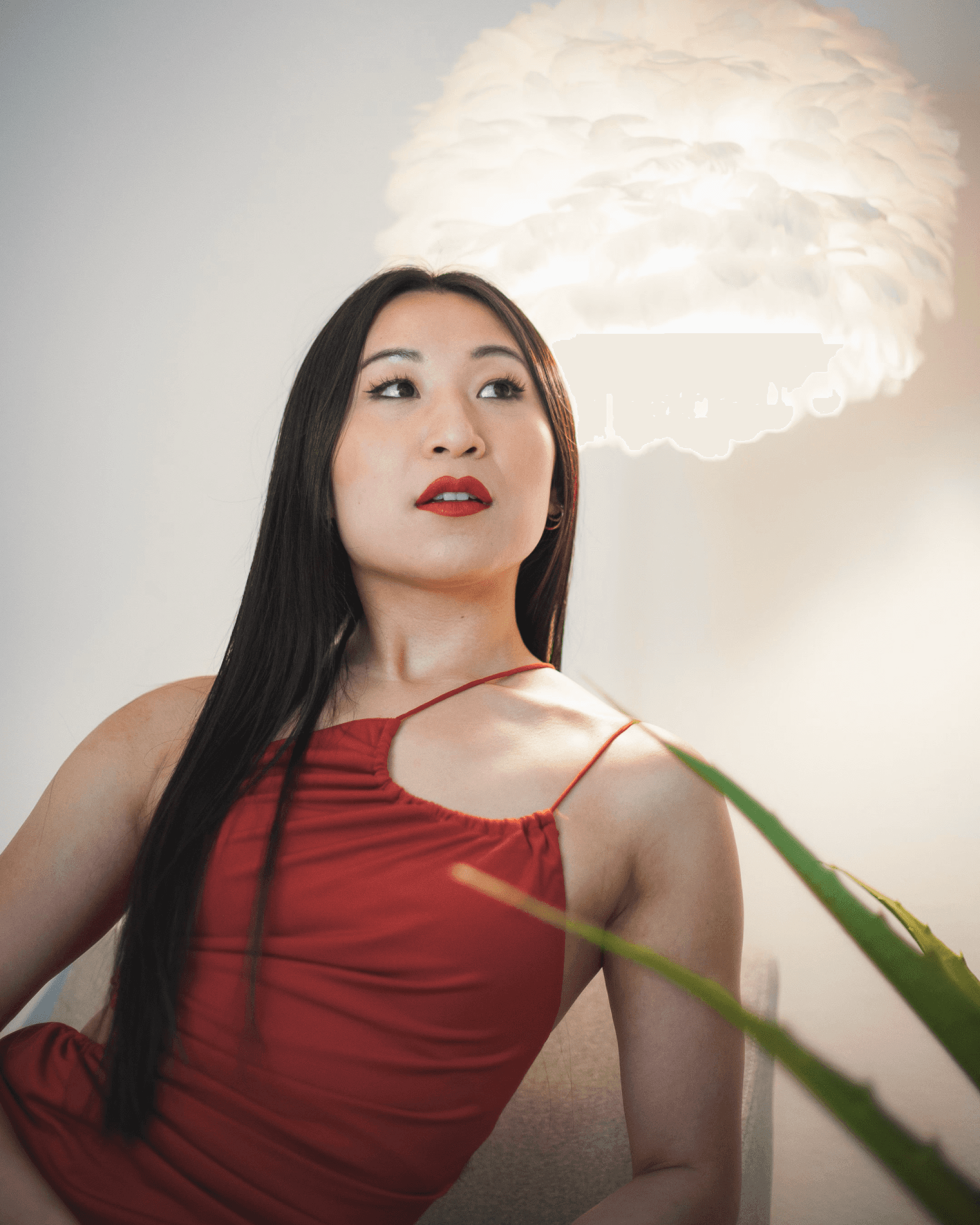 Portrait of a woman in a red top standing outdoors against a dramatic sky and green hillside