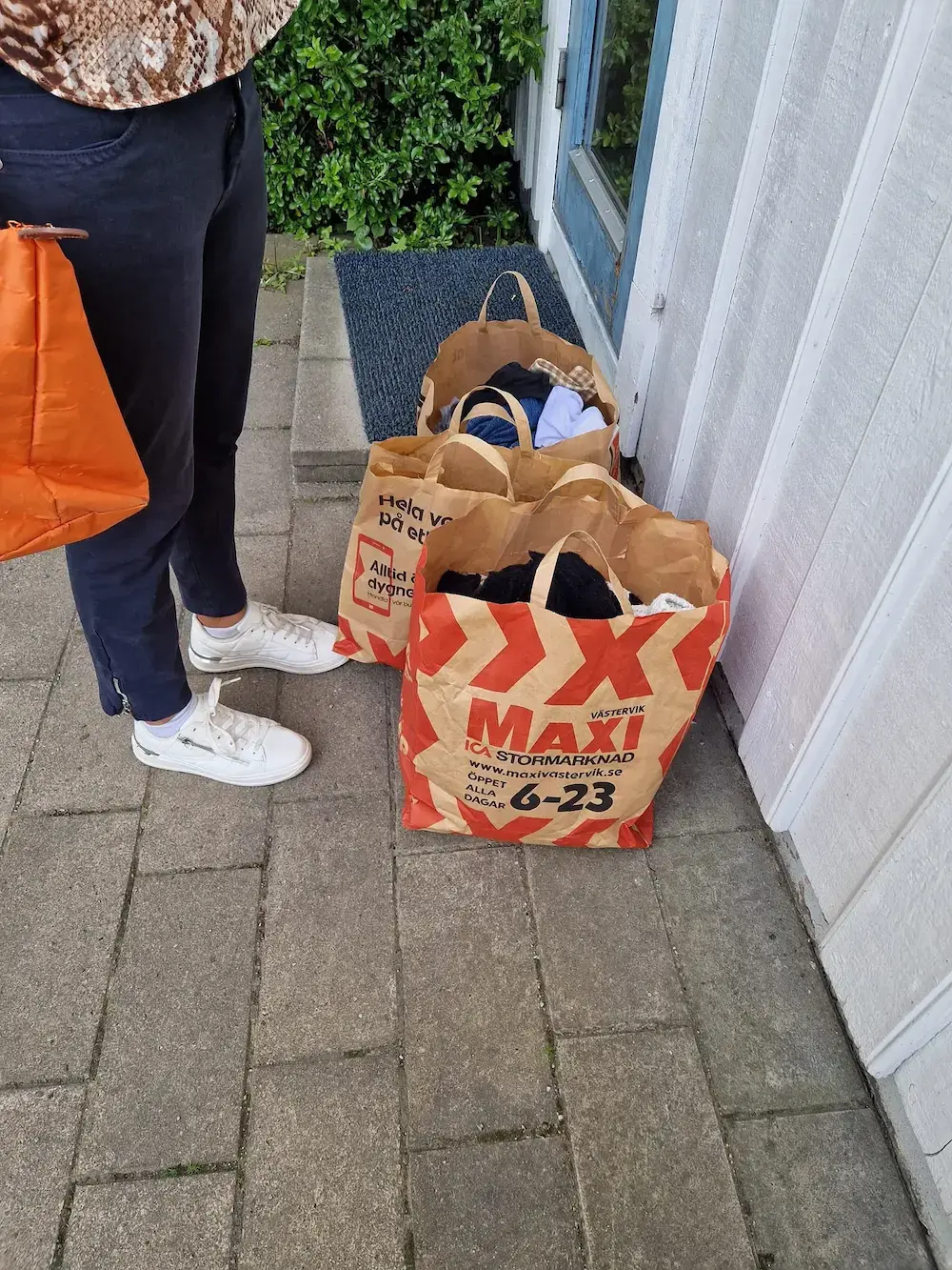 Papperskassar med donerade kläder står utanför en entré.