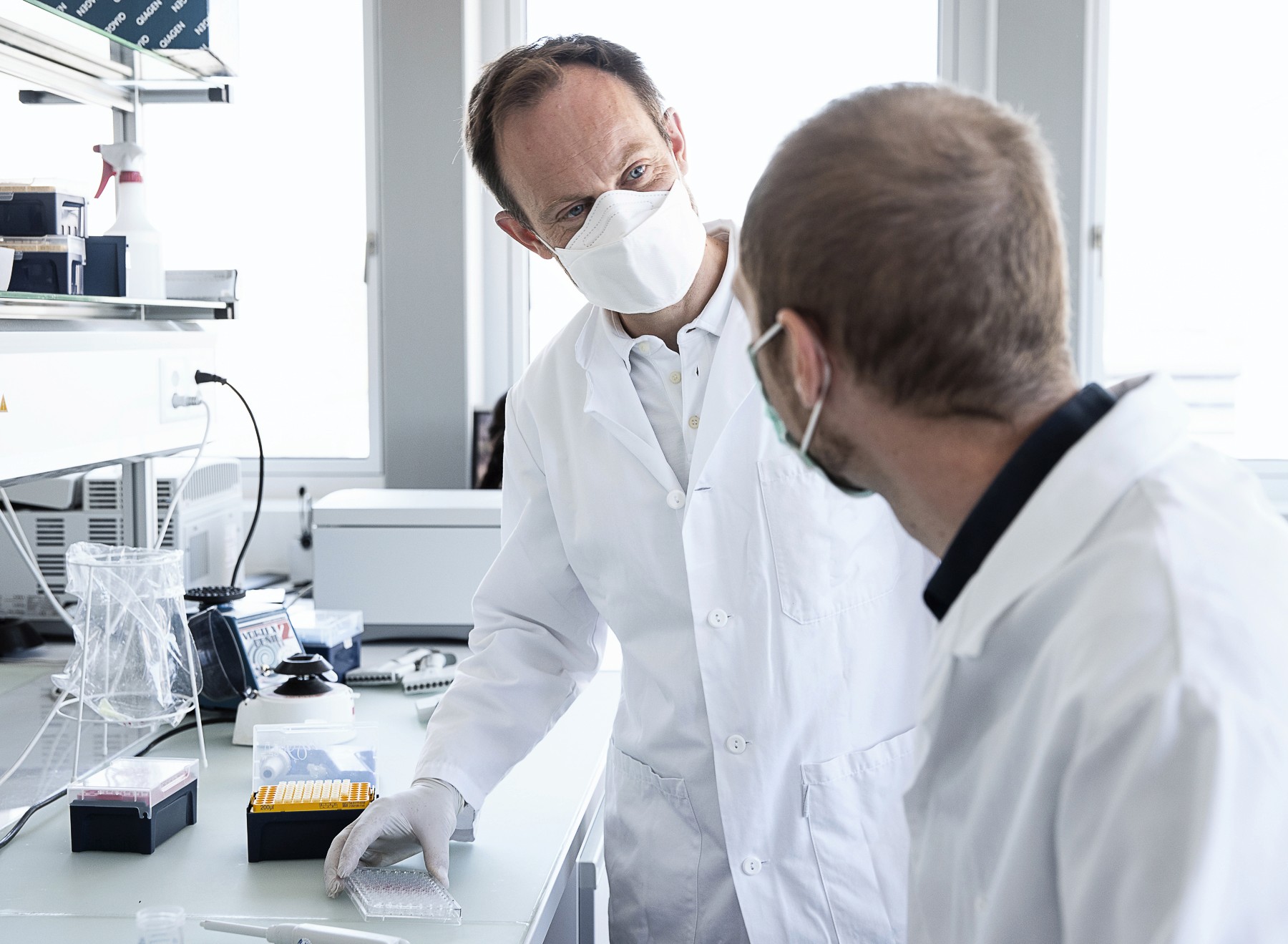 Modern office interior with glass walls, wooden accents, and a person walking up a staircase in motion blur.