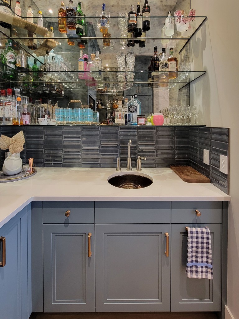Image of Luxurious home bar design with gray cabinets, marble countertop, and elegant shelving by KHD Homes.