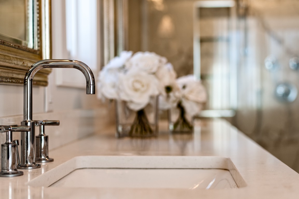 Image of Luxury bathroom sink with modern faucet and white roses on marble countertop, KHD Homes design.
