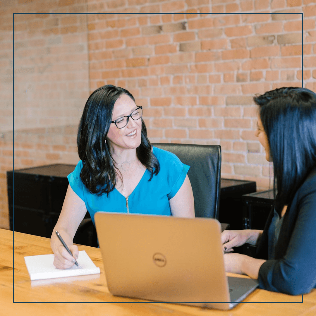 Zwei Frauen sitzen an einem Tisch mit Laptop vior sich
