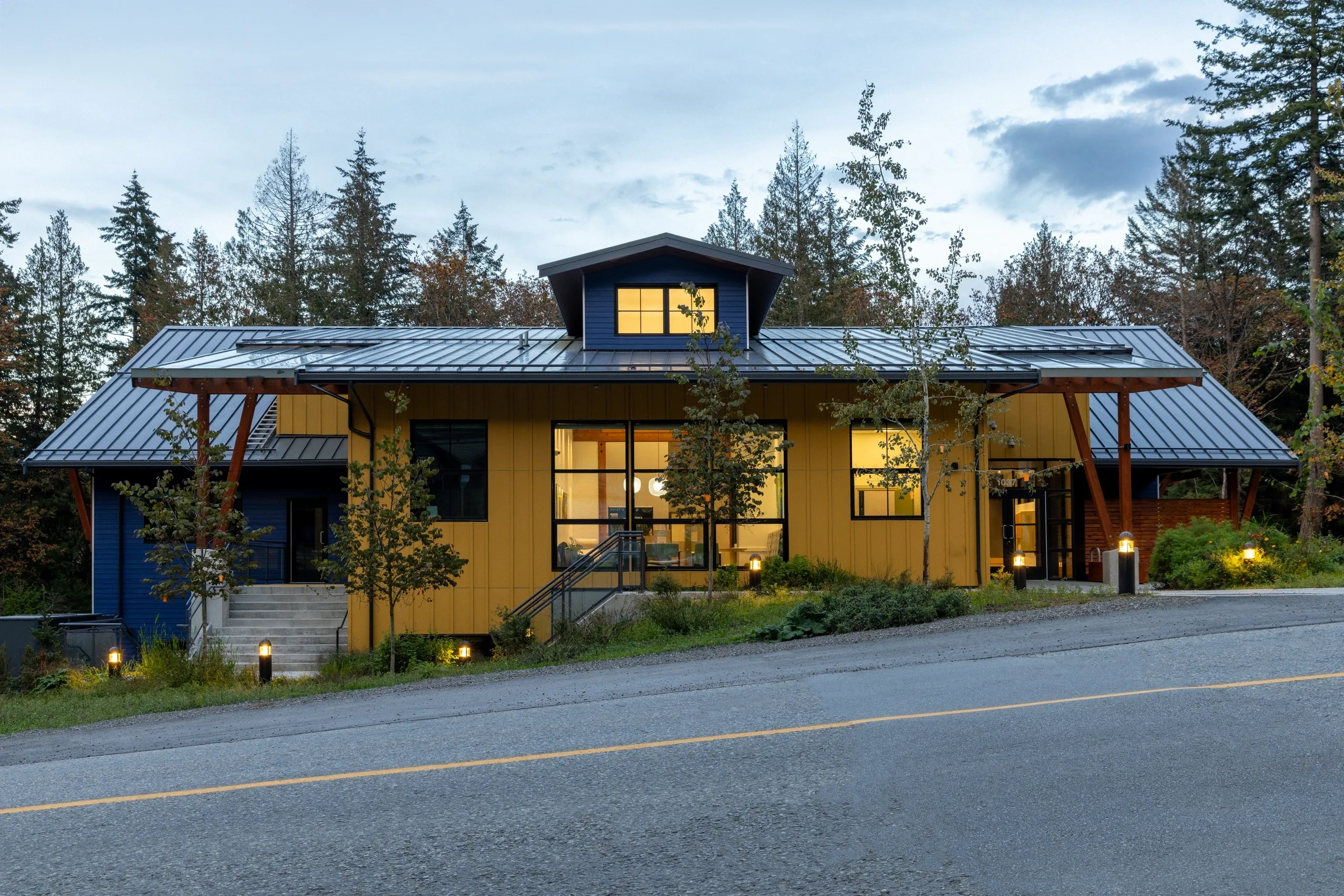 Contemporary home with custom windows and doors near a lush forest setting.