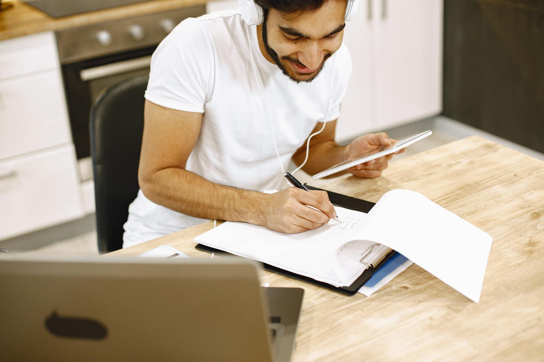 Side-by-side comparison of a sleek laptop screen and a spiral-bound paper planner on a marble tabletop.
