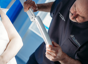 Dr. Adam Friedmann using a magnifying lamp for a skin check.