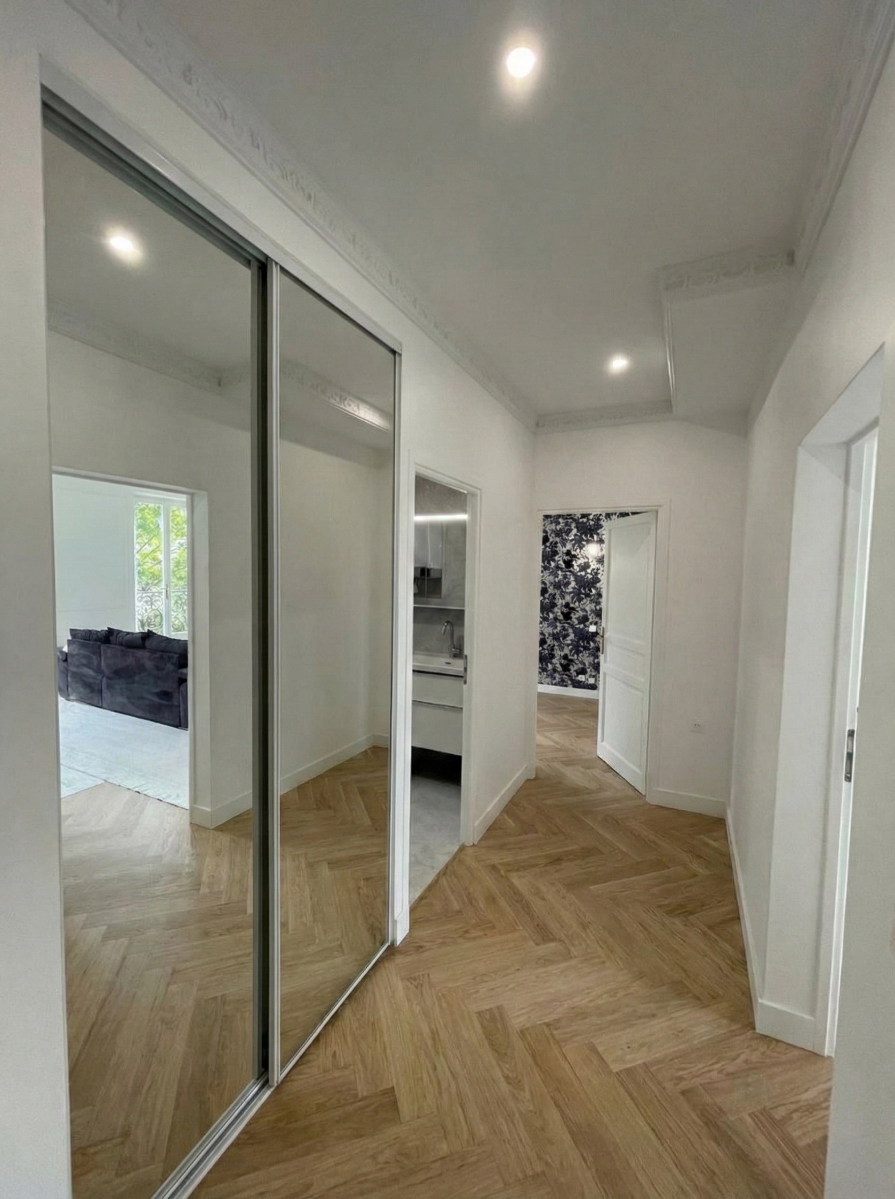 Couloir d'entrée optimisé avec grands placards miroirs toute hauteur pour agrandir visuellement l'espace.