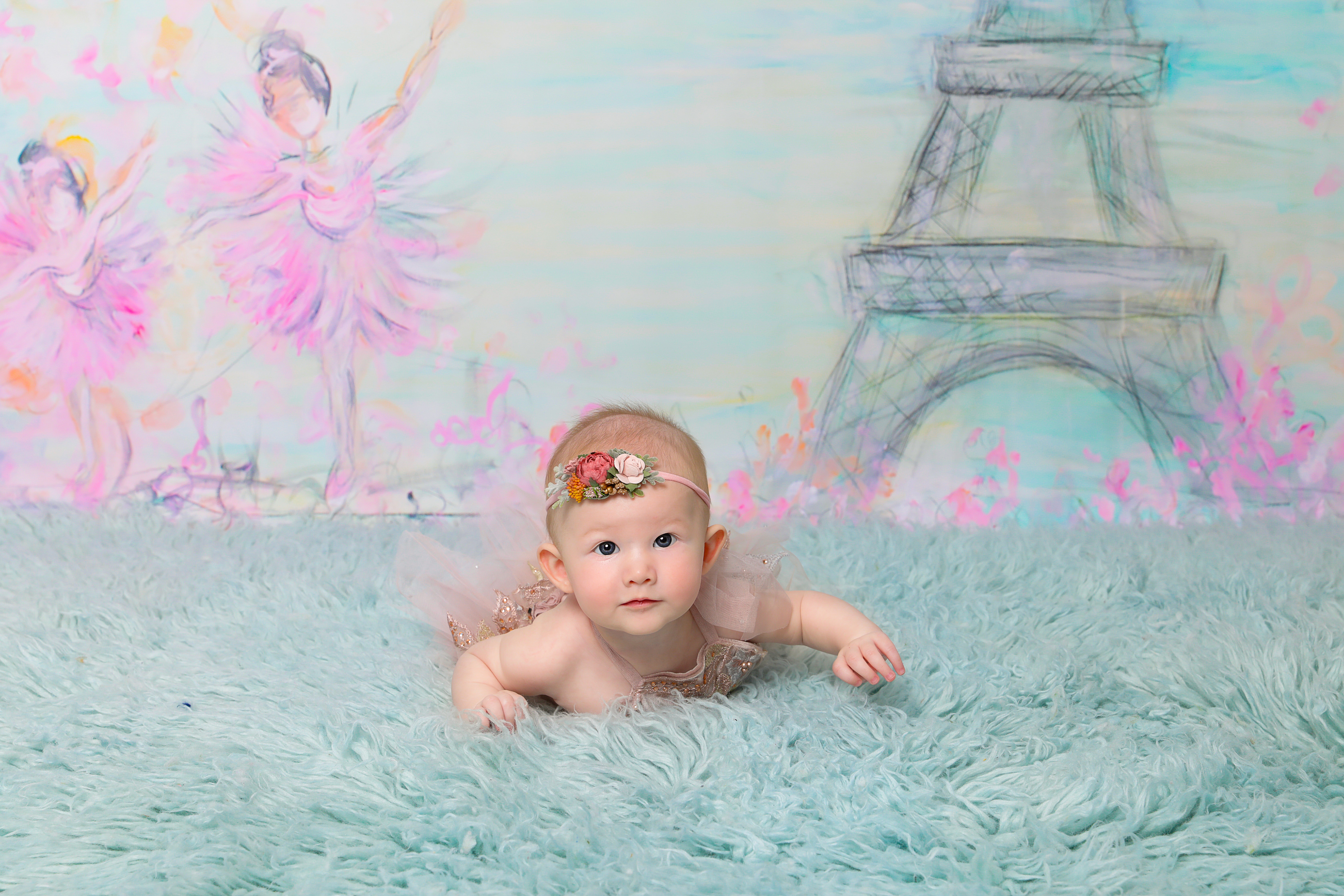 Baby girl laying flat on tummy , common during newborn photoshoot age months four to five.