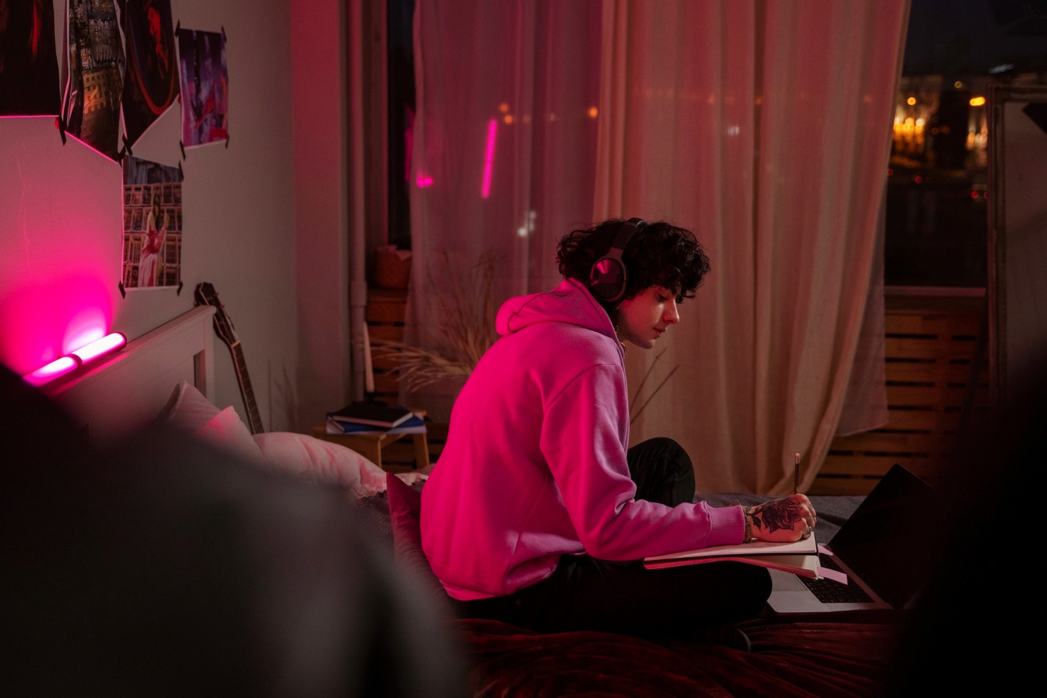 A person seated on a bed, focused on their laptop, surrounded by a cozy bedroom atmosphere.